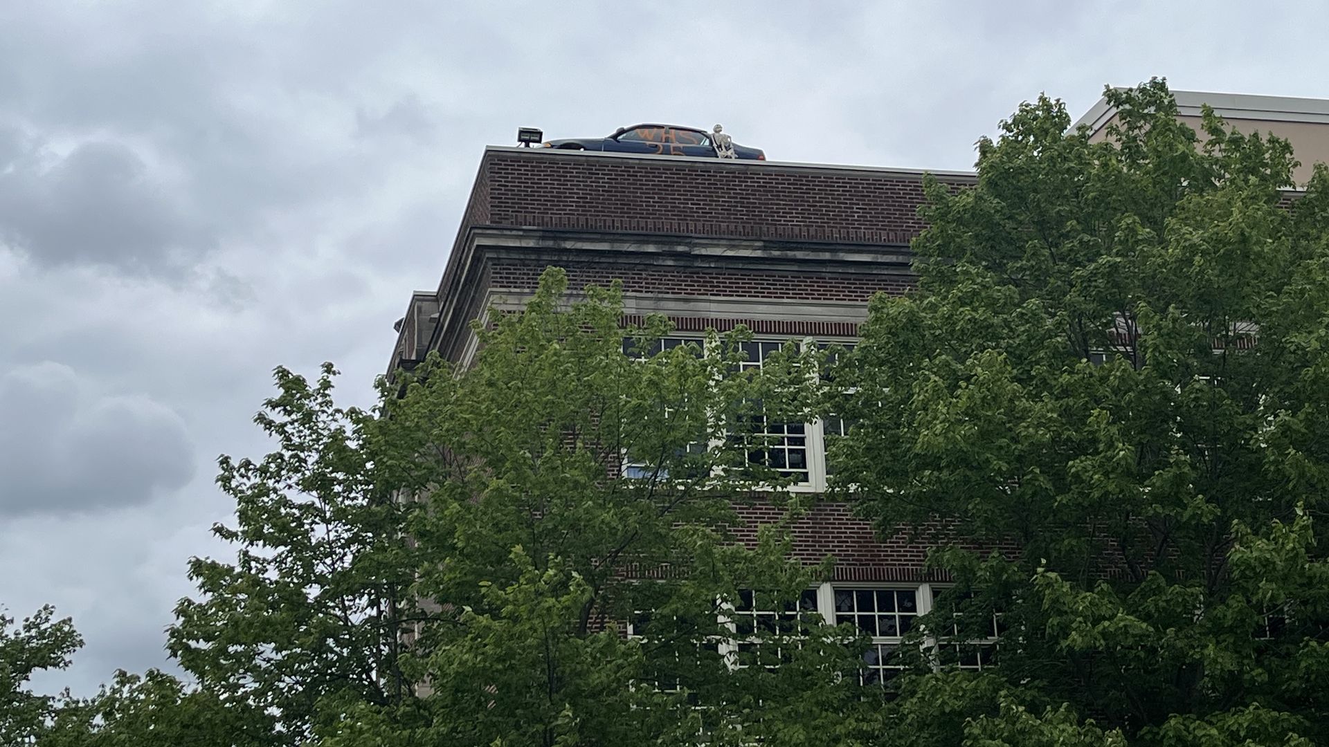 A photo showing a car on the roof of a school 
