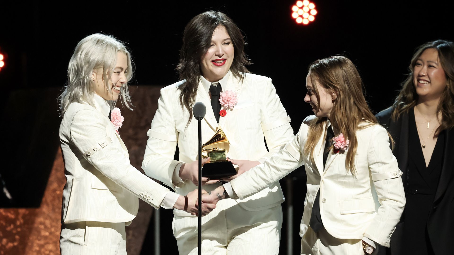 A picture of boygenius accepting a Grammy in white suits.