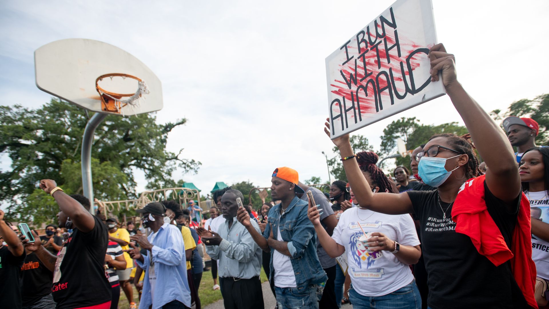 A person in a T shirt holds a sign that reads: "I run with Ahmaud"