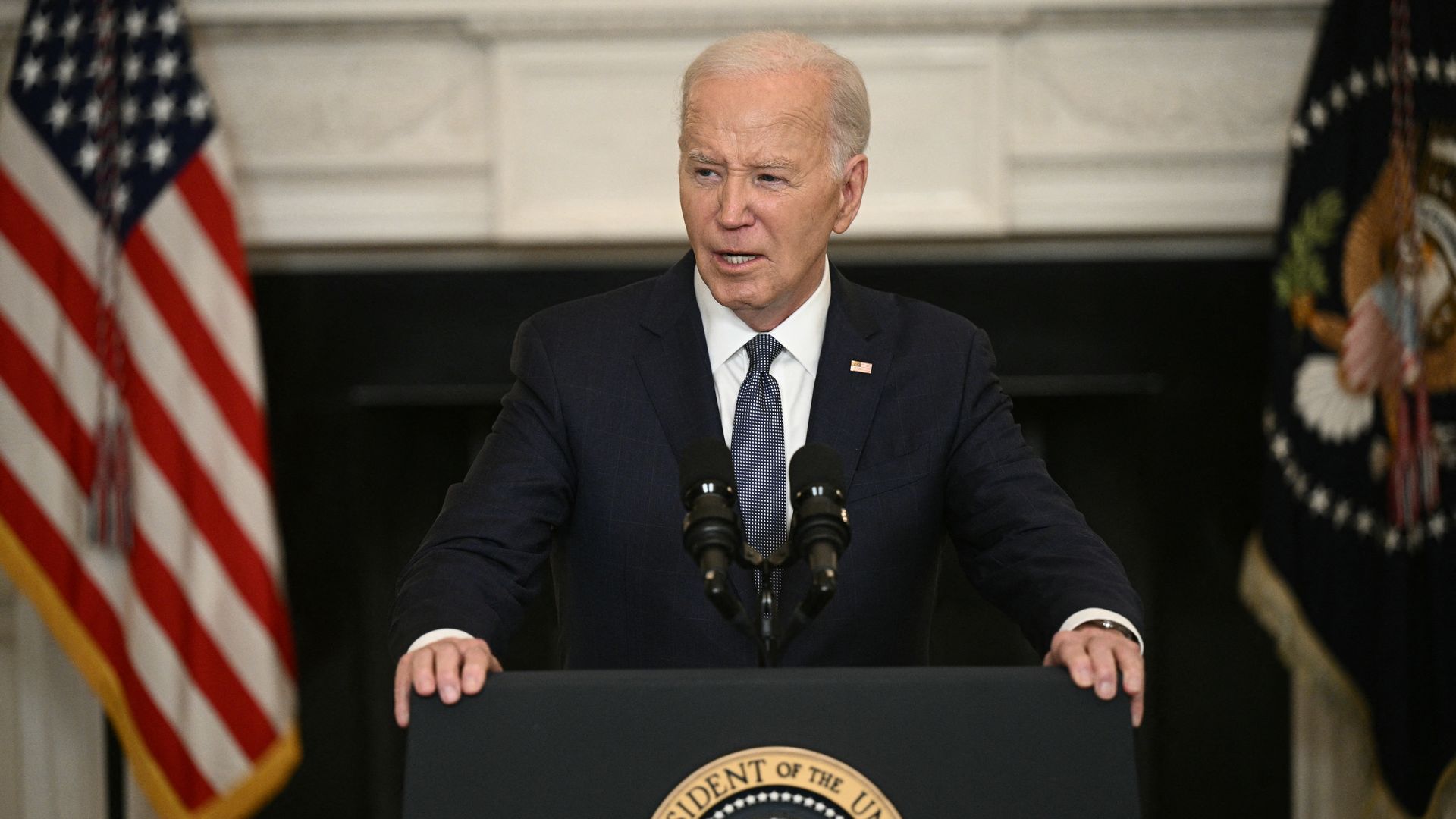 President Joe Biden, wearing a blue suit and speaking at a podium at the White House.