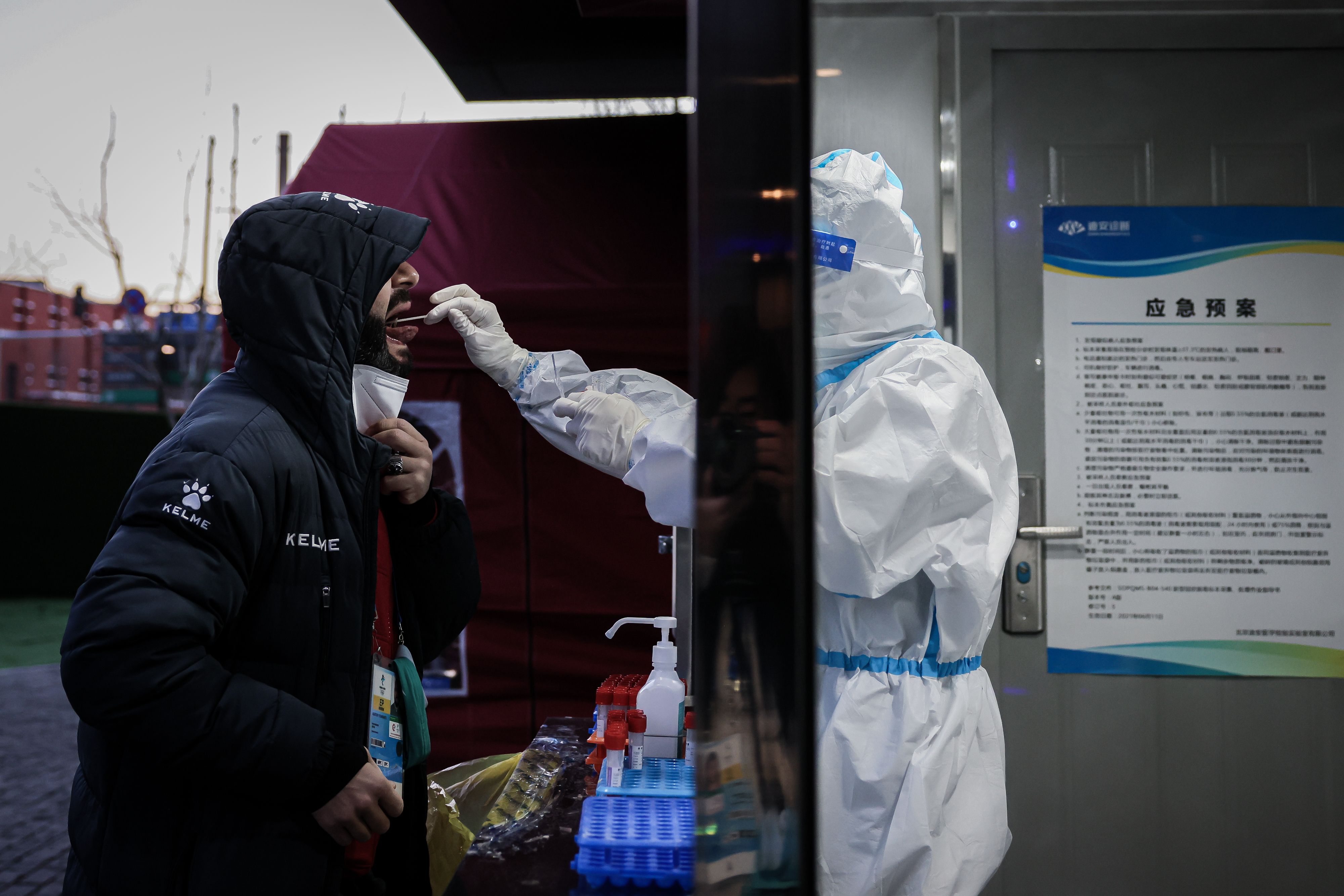 A medical staff in personal protective equipment collects a daily mandatory COVID-19 swab sample from member of the media on February 04, 2022 in Beijing, China.