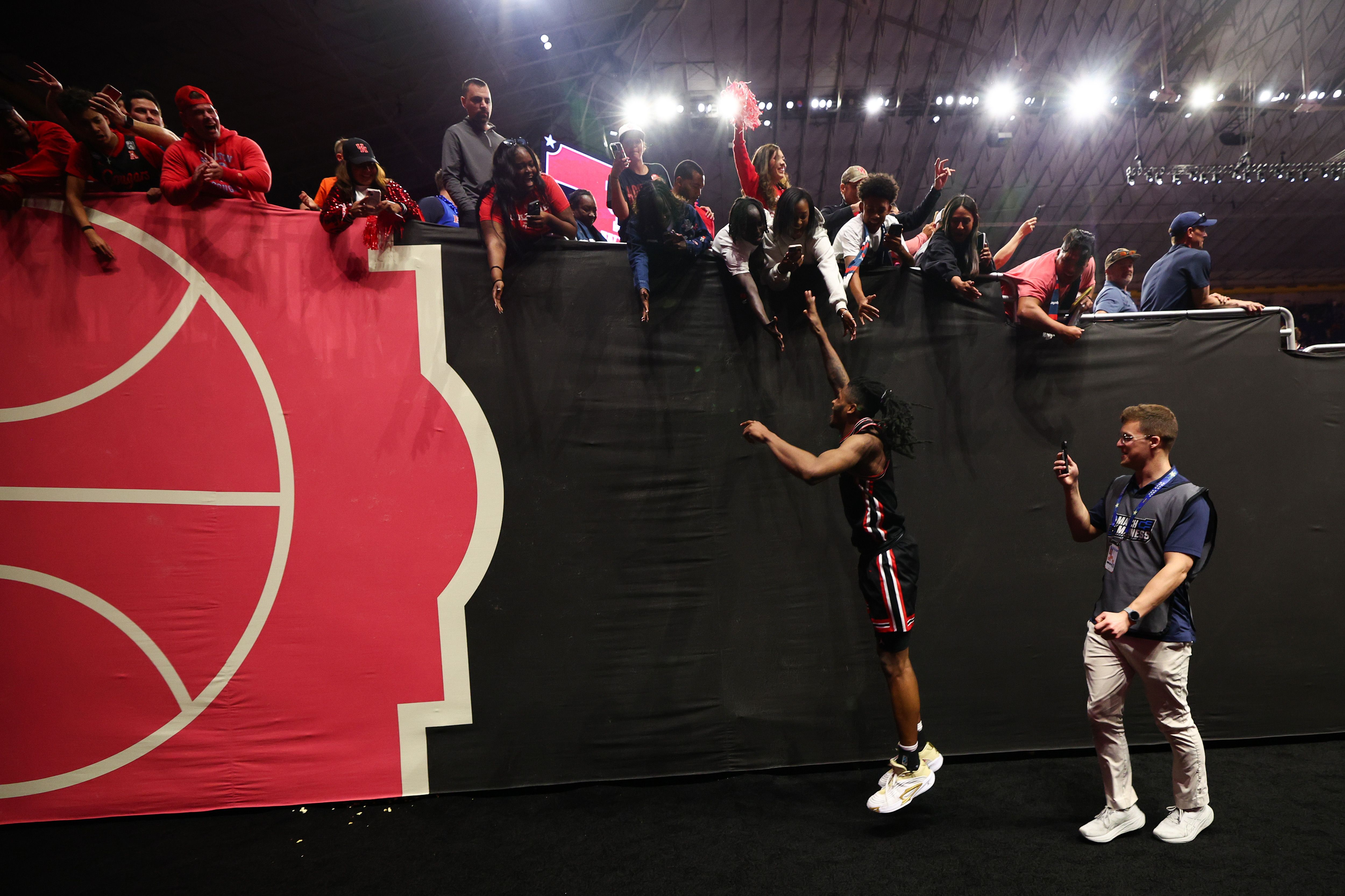 The Houston Cougars celebrate a win by jumping up to meet fans' hands at the Alamodome.