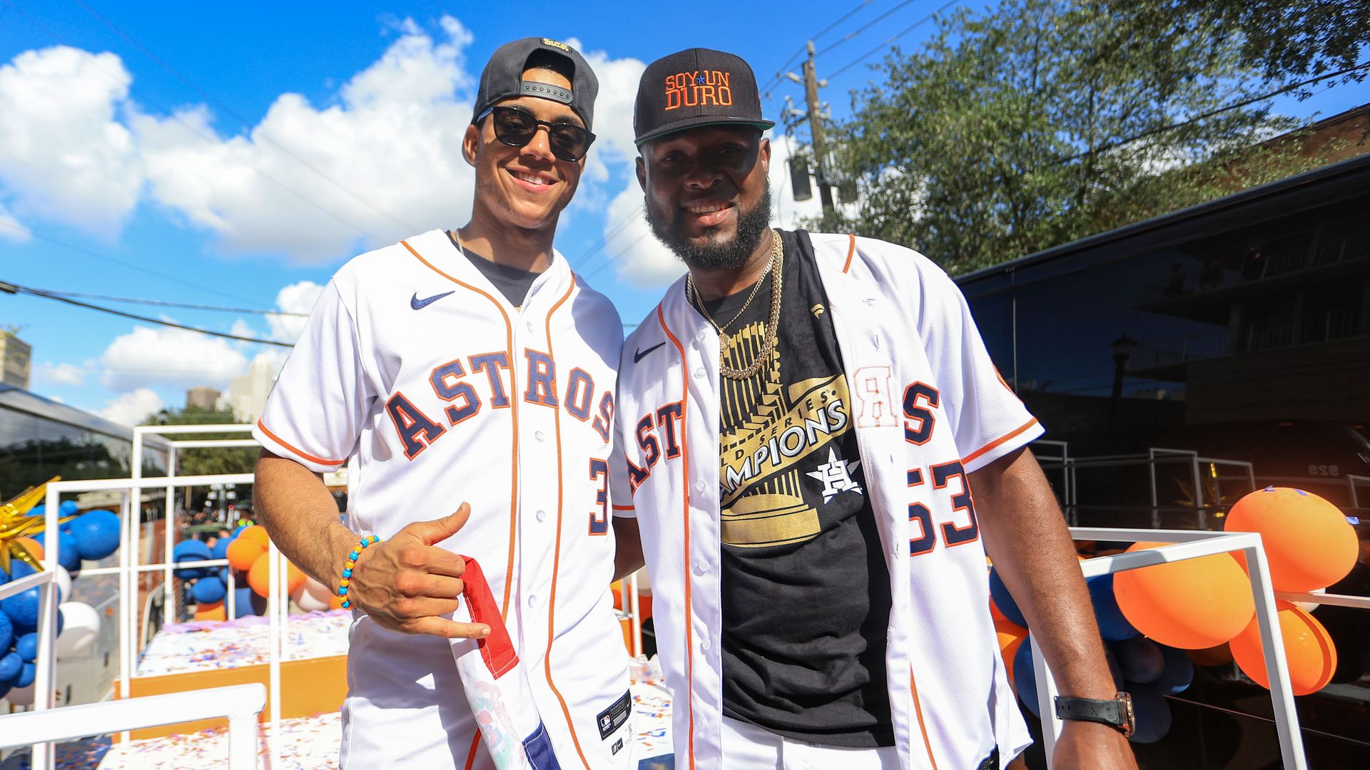 Astros players Jeremy Peña and Cristian Javier, wearing white Astros jerseys, pose for a photo atop a float during the 2022 World Series parade in Houston