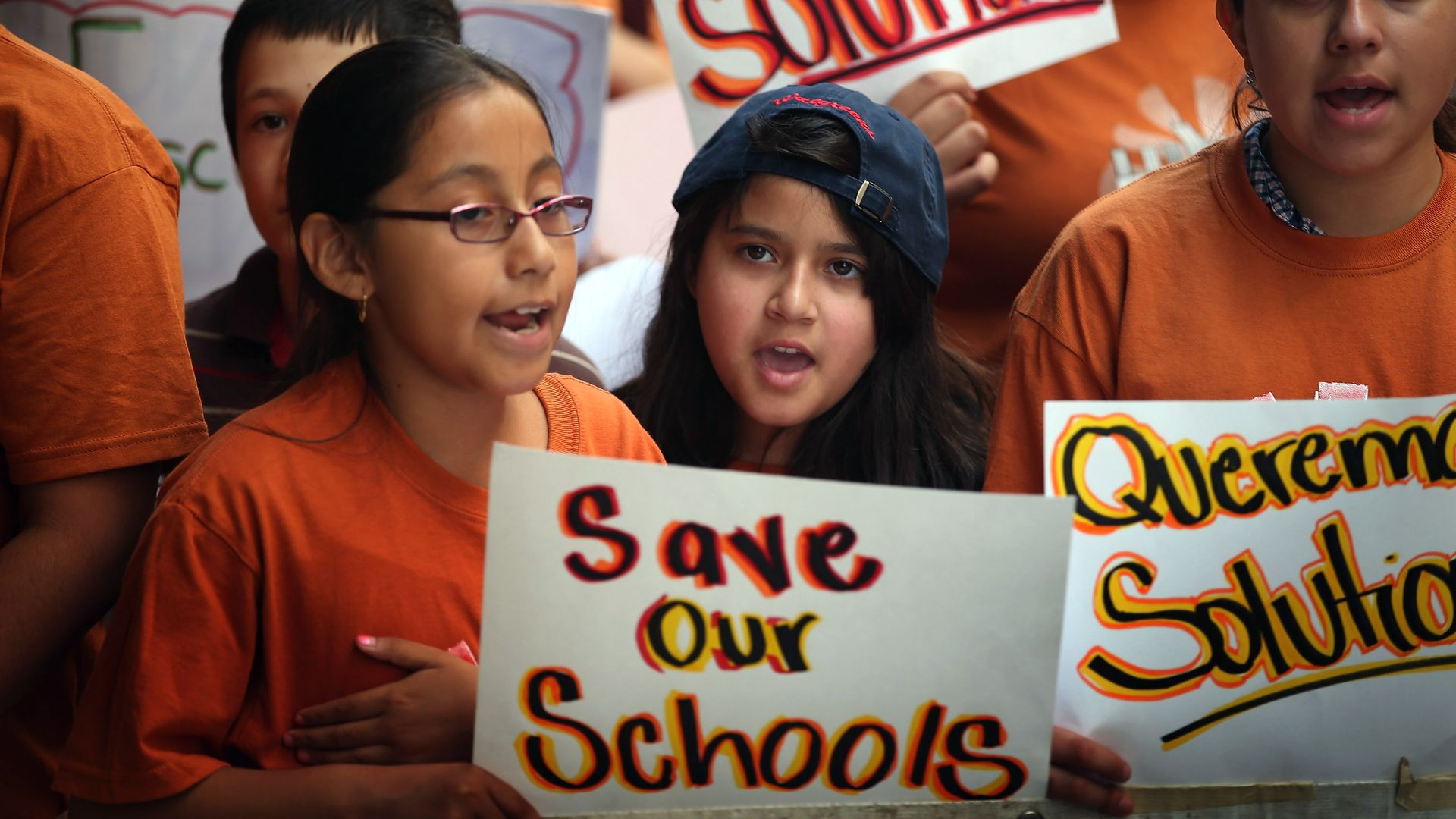 Kids with a sign that says," Save our schools."
