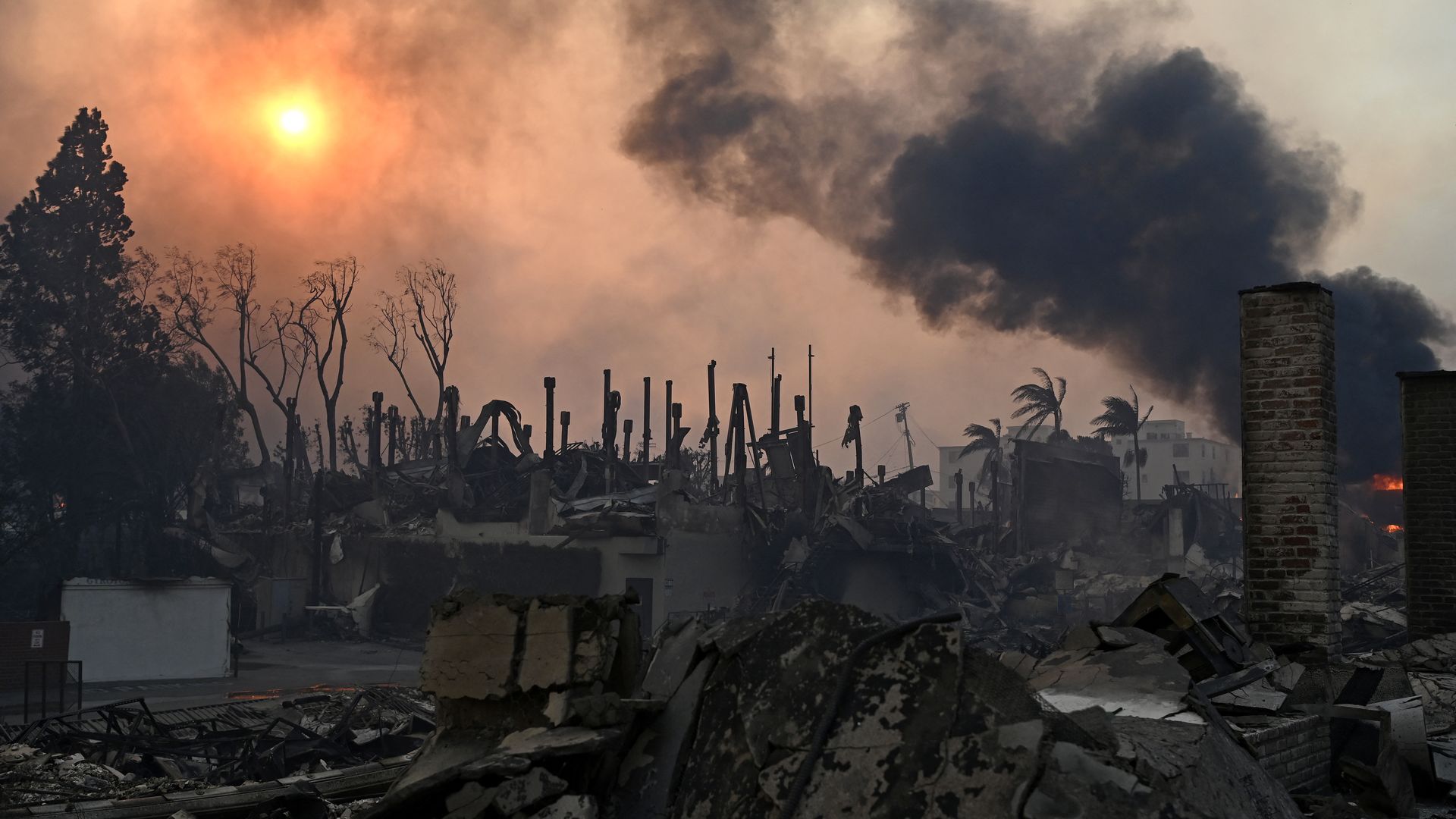 Photo of burned rubble and smoke billowing into the air after a fire