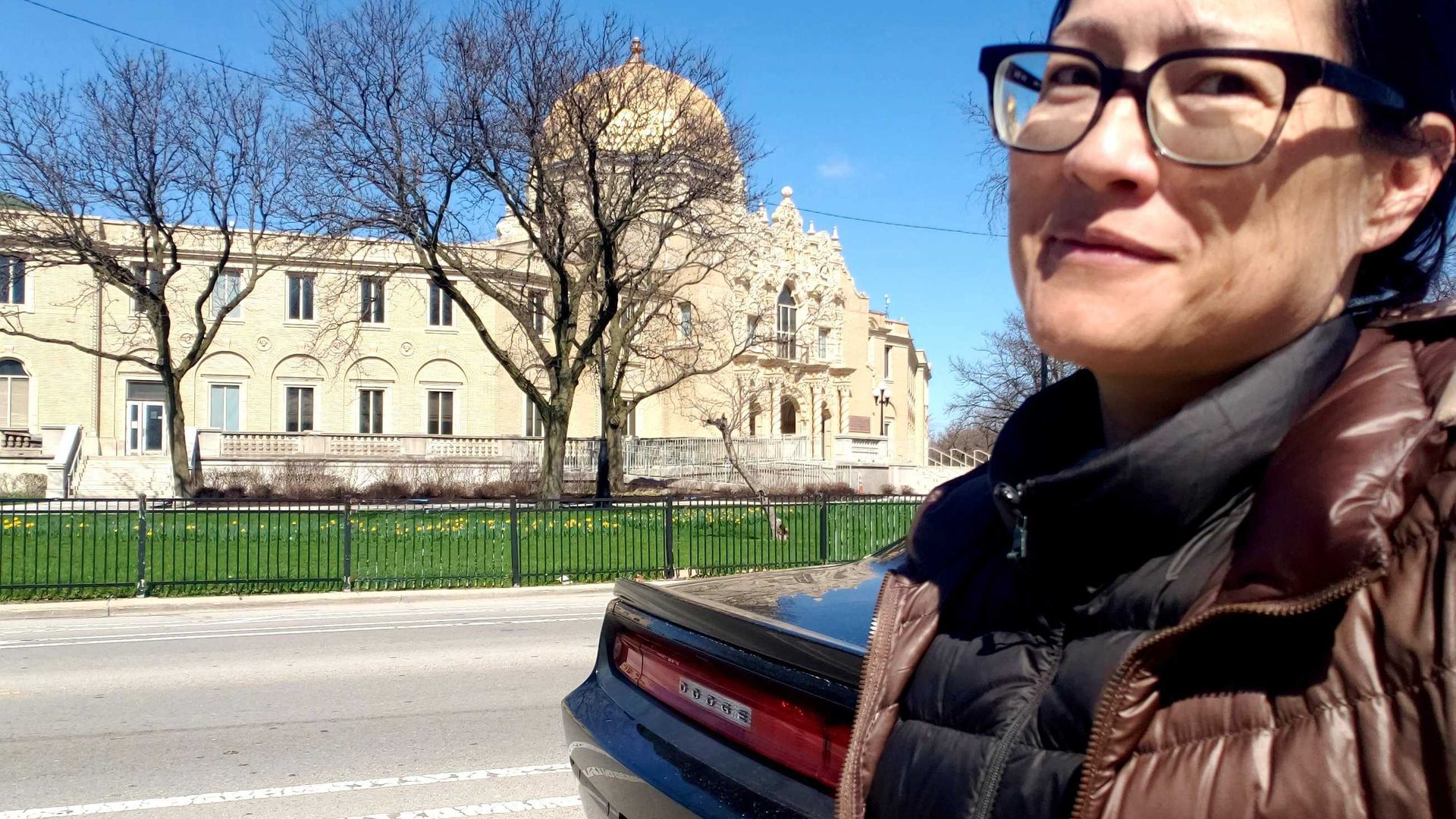 Photo of a woman standing in front of a building with a gold dome. 