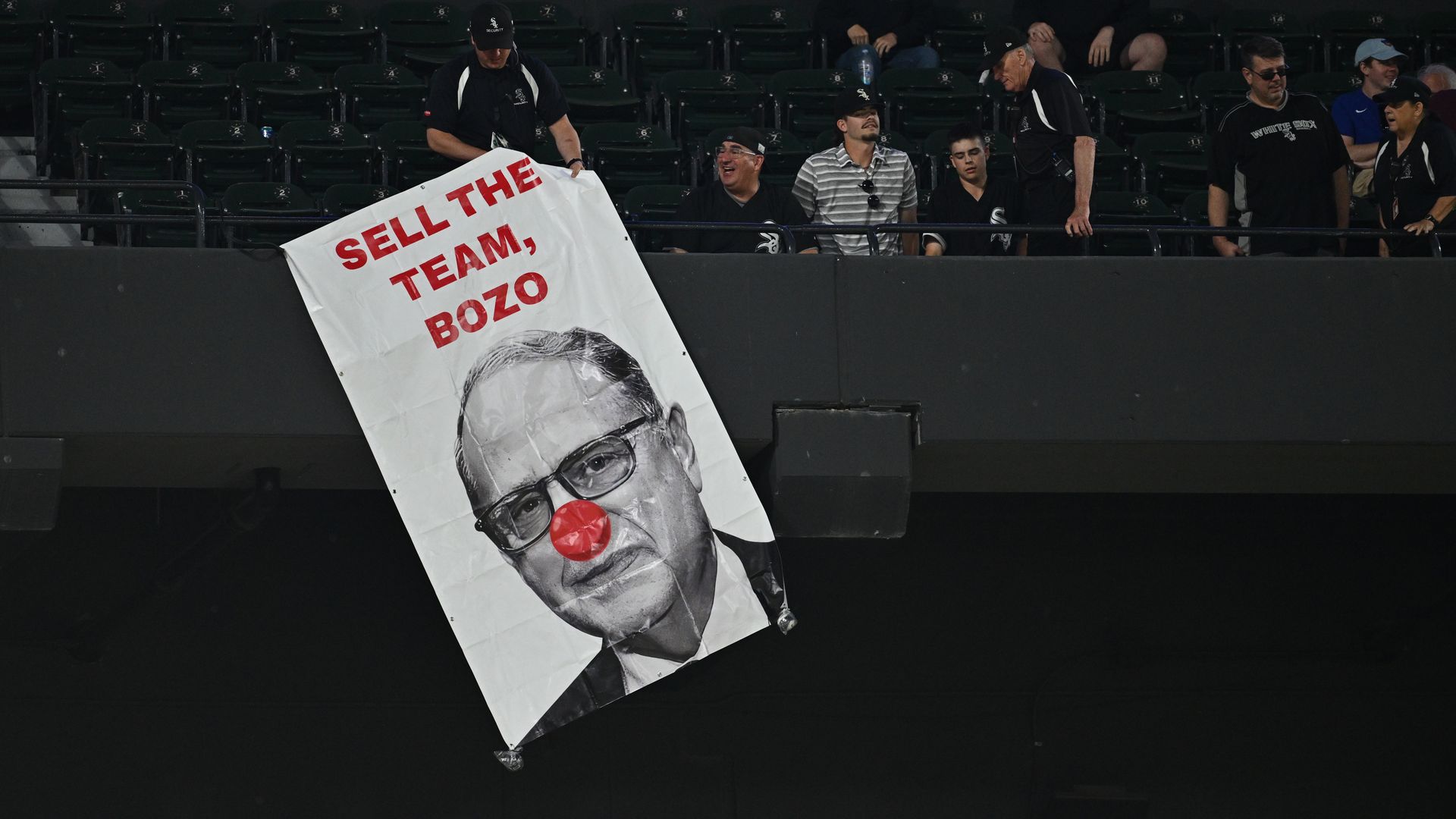 Photo of a man holding a banner that says "Sell the team, bozo" 