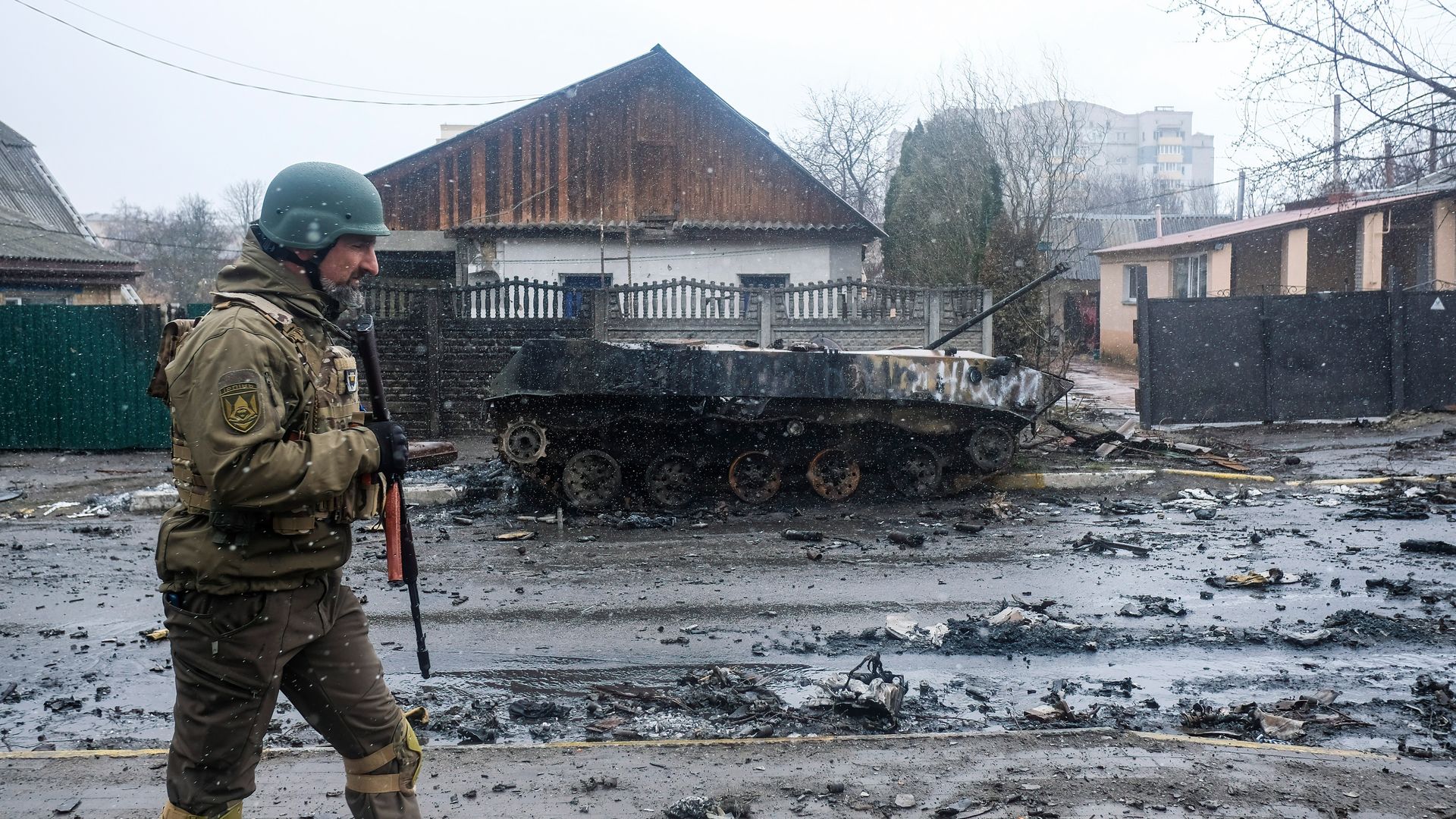 Ukrainian soldier inspects the wreckage of a destroyed Russian armored column on the road in Bucha