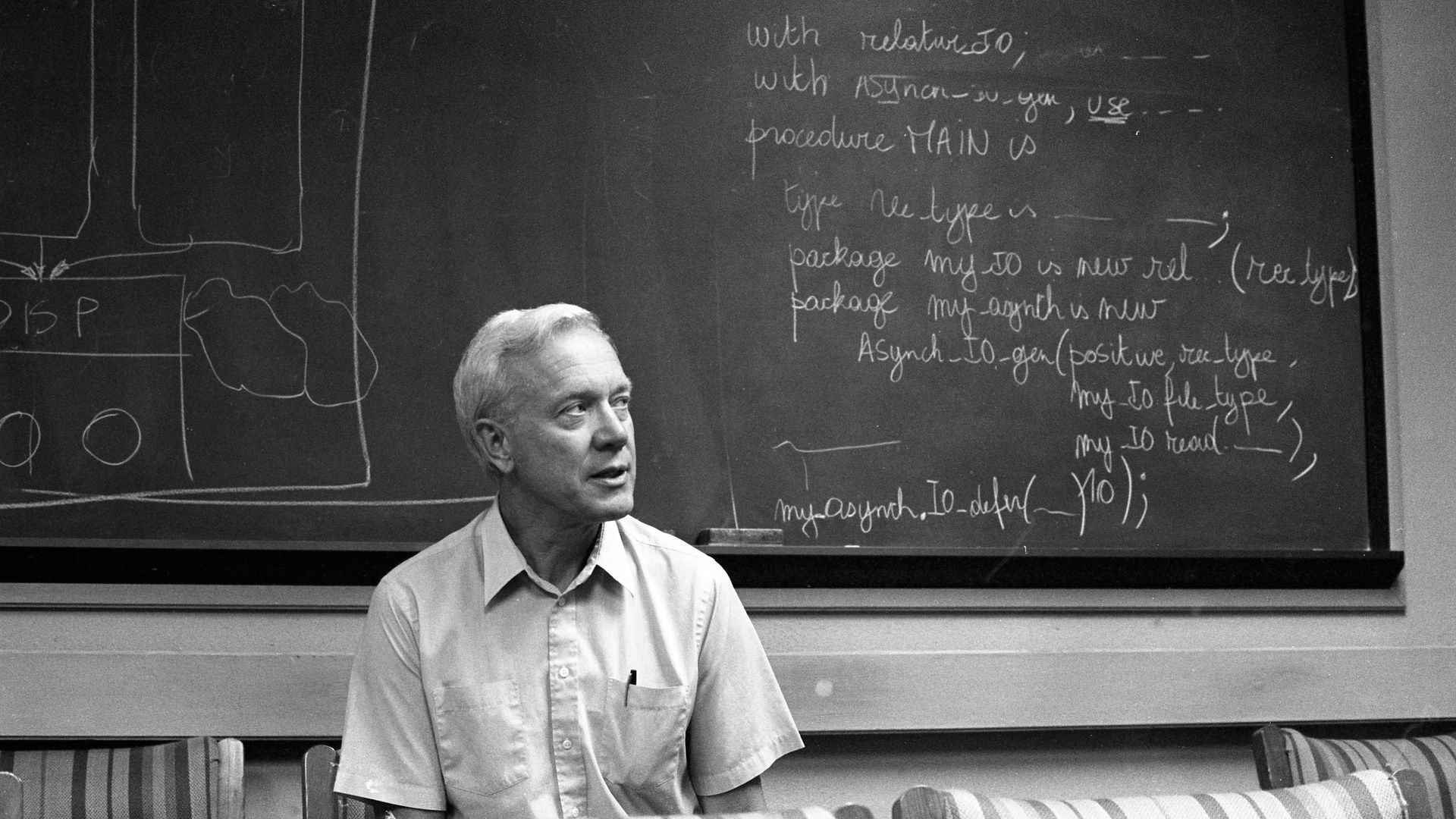Photo of a man sitting in front of a blackboard