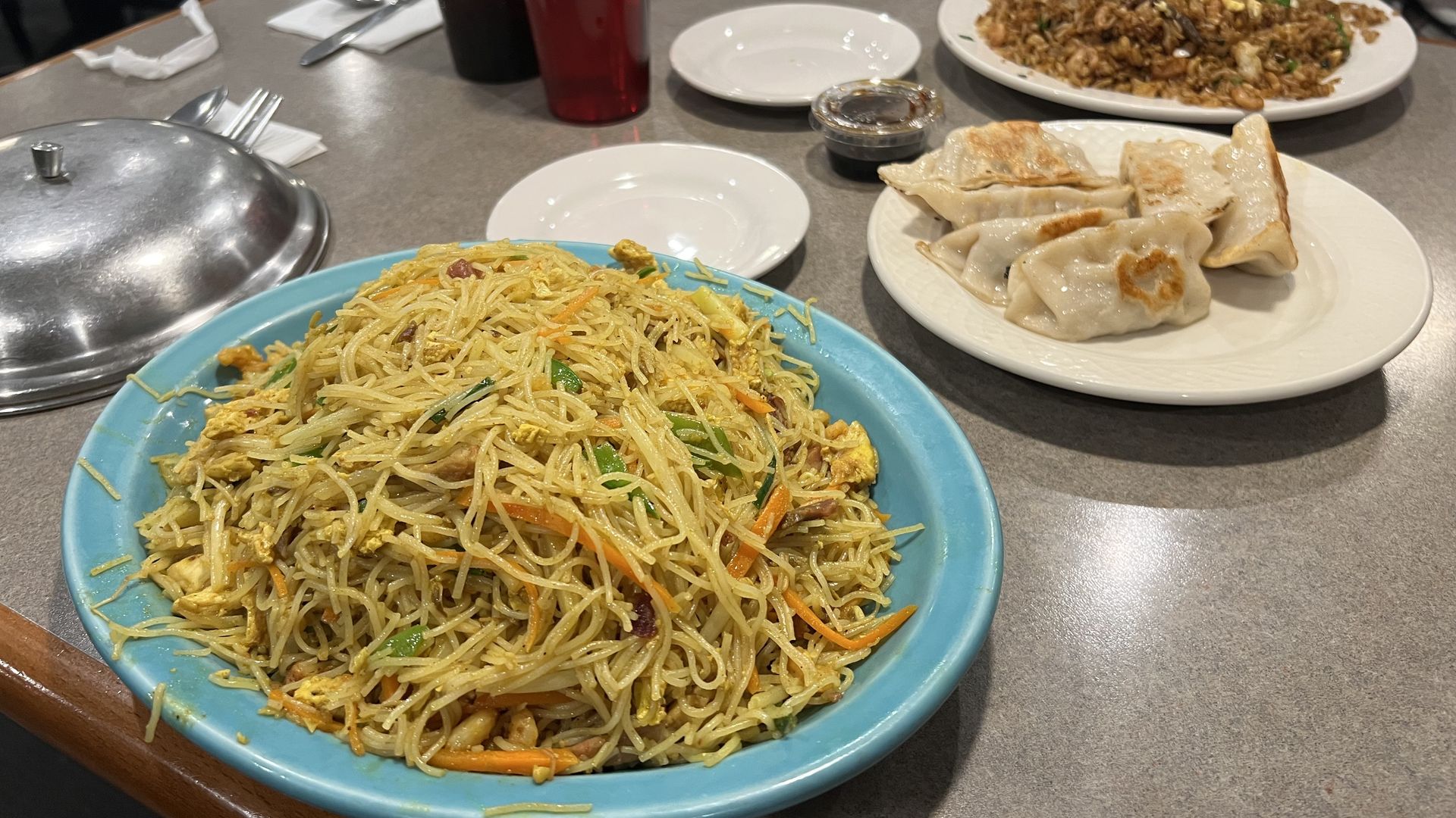 An order of spicy Singapore curry lo mein noodles, potstickers, and fried rice on a restaurant table