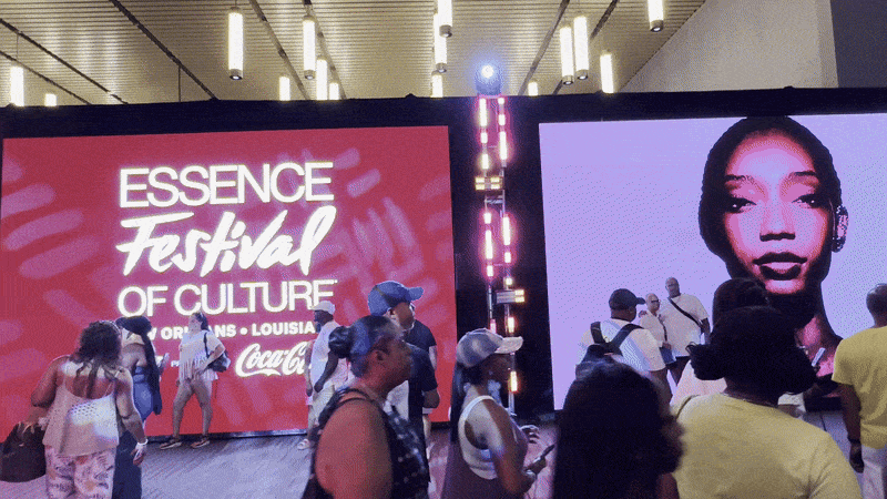 Image shows people walking in front of an Essence sign.