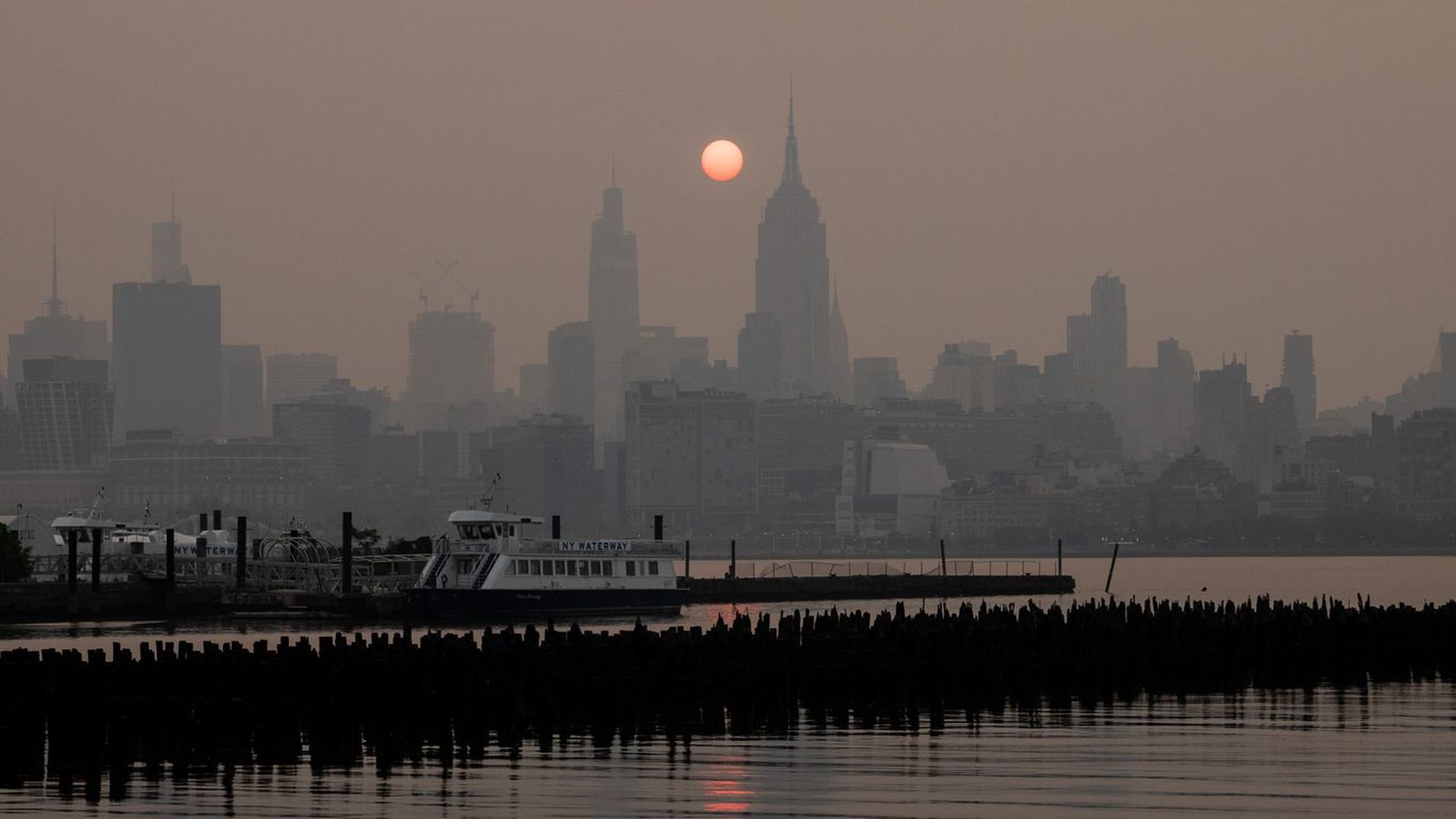 The Manhattan skyine shrouded in smoke from Canada wildfires at sunrise in Jersey City, New Jersey