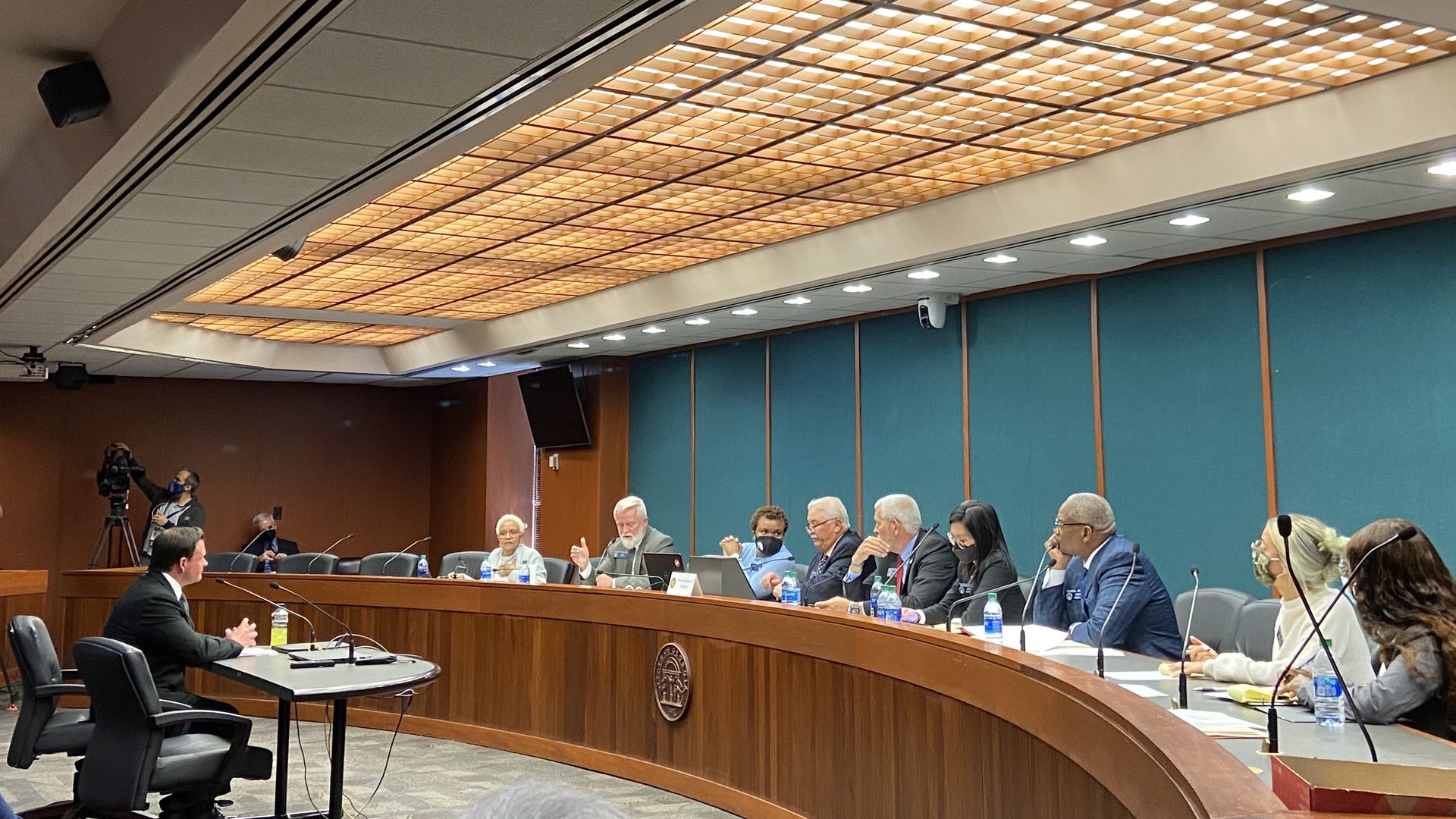 Man at a table sitting before a dais of state senators in committee
