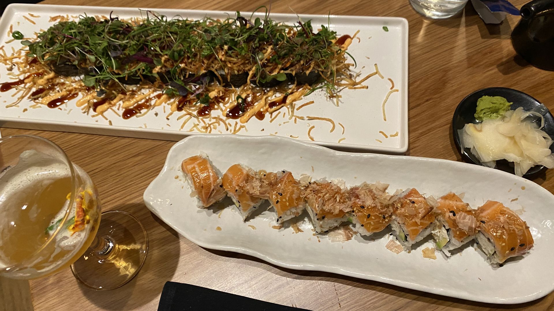 Two sushi rolls displayed on long, narrow plates. 
