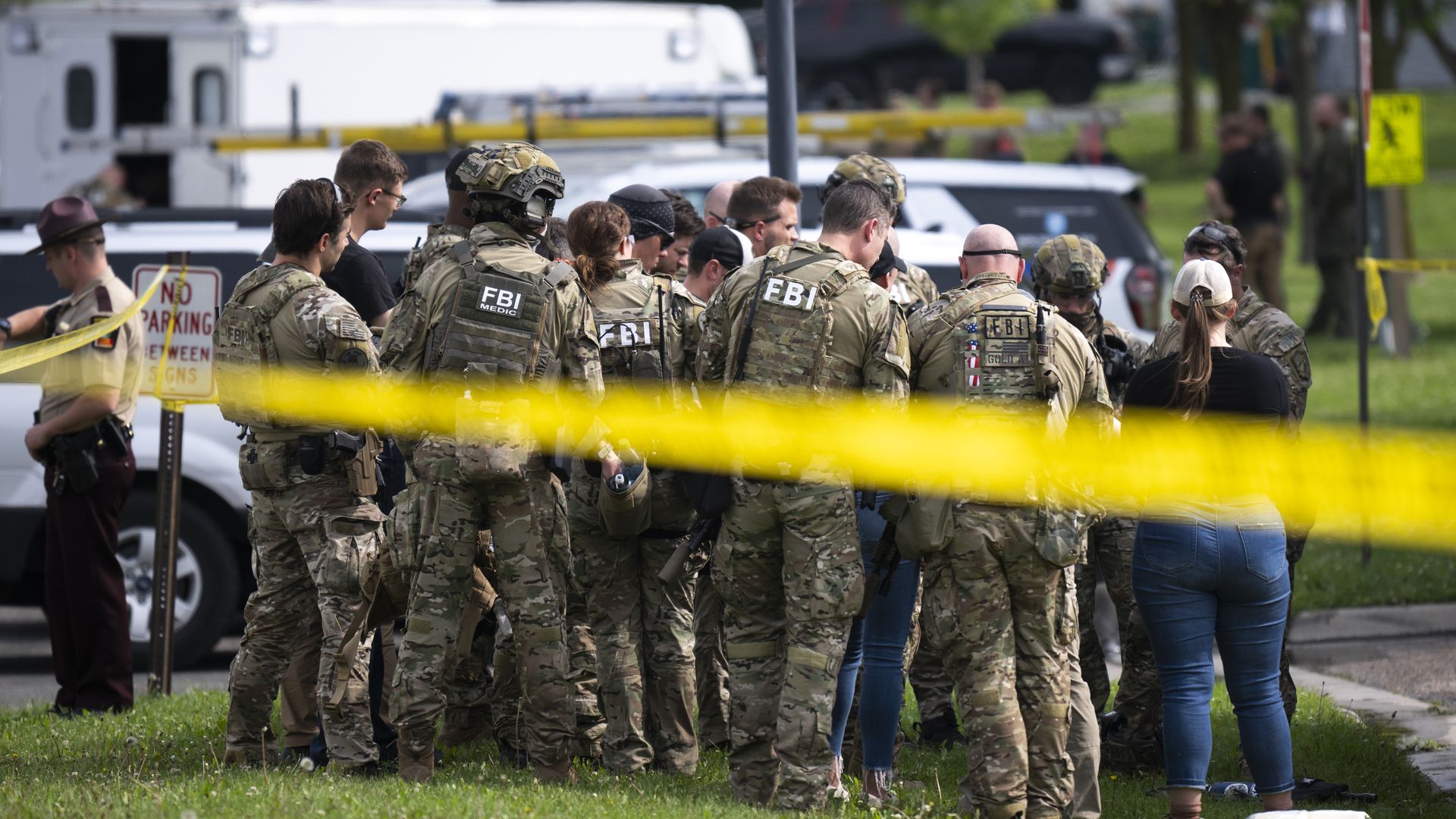 A group of FBI agents stand together behind yellow tape.