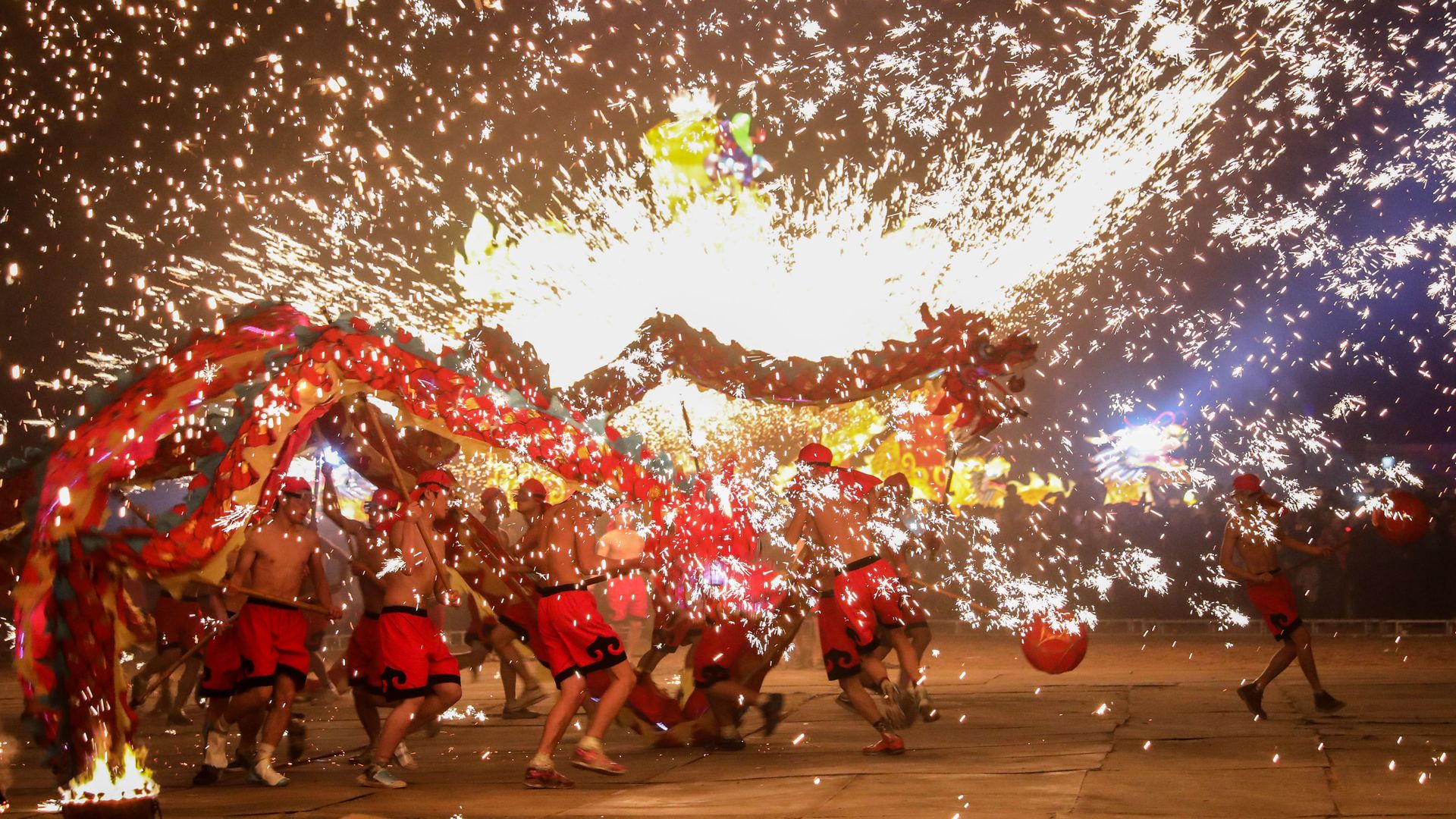 People perform dragon dance in the splash of molten iron to celebrate the Spring Festival in a traditional way in Yongcheng in central China's Henan province Tuesday Feb. 20, 2018