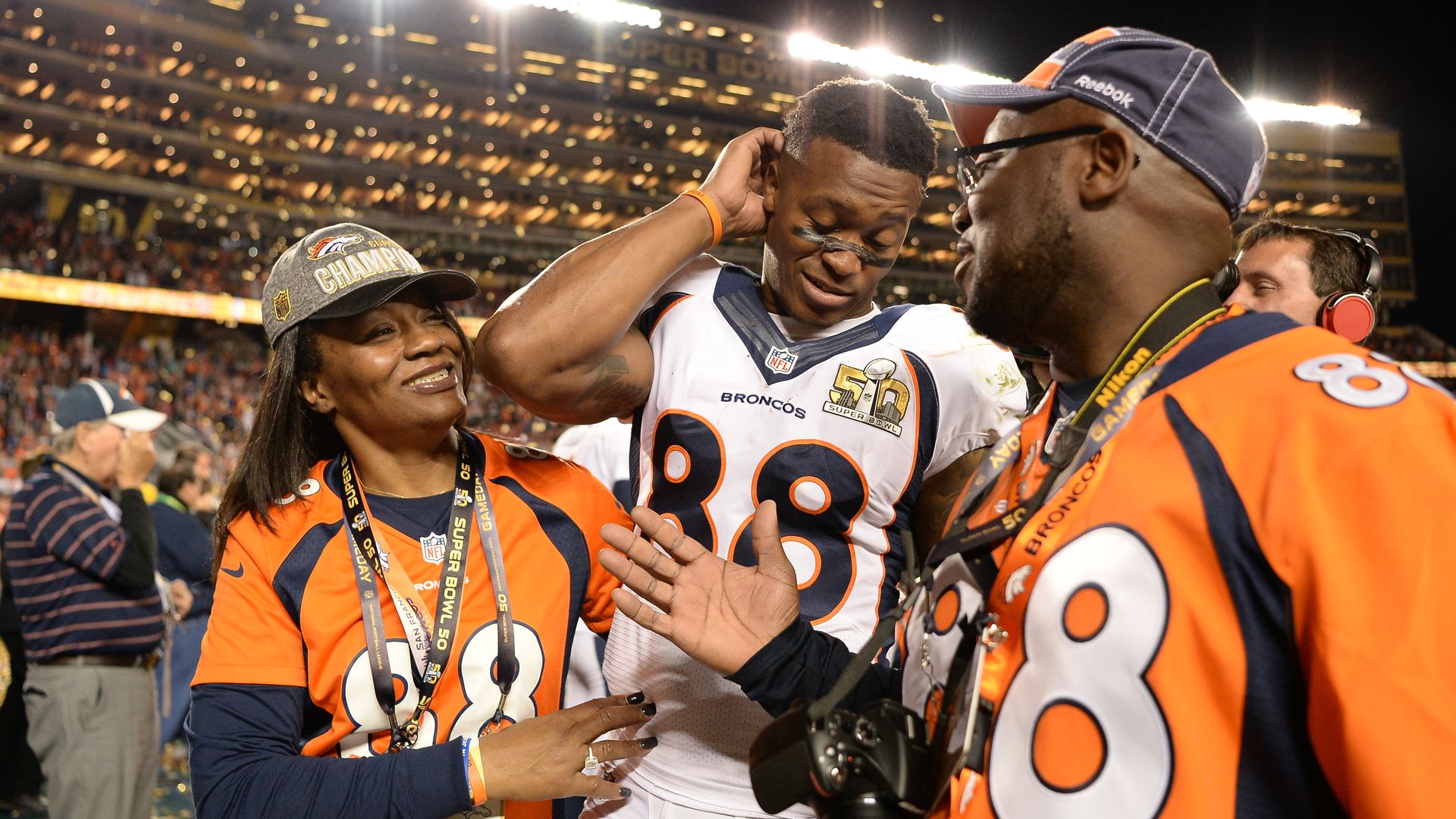 Demaryius Thomas smiles looking down as he stands with his mother and father after a game as they smile and congratulate him