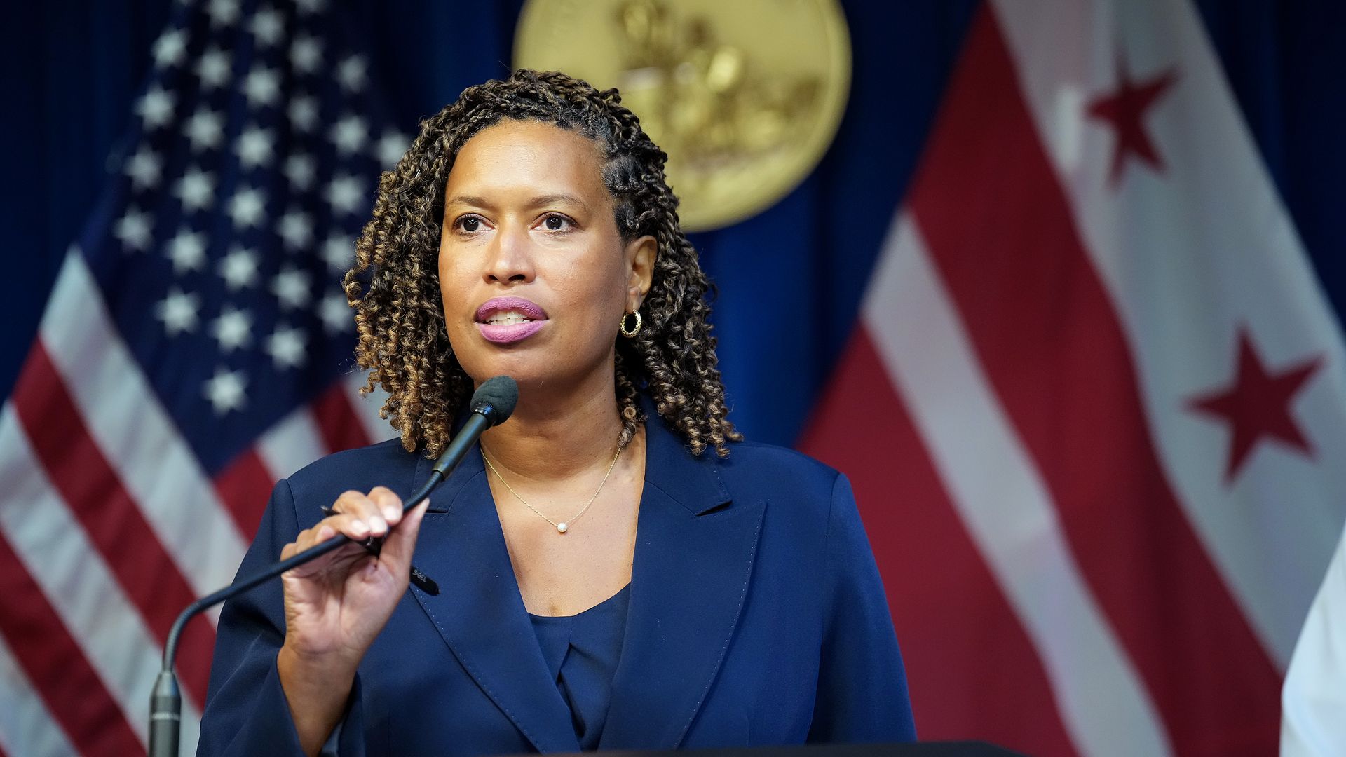 Muriel Bowser at a podium with the U.S. and D.C. flags behind her