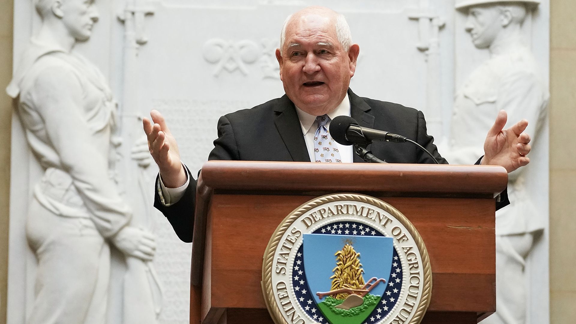 In this image, Sonny Perdue speaks at a podium.