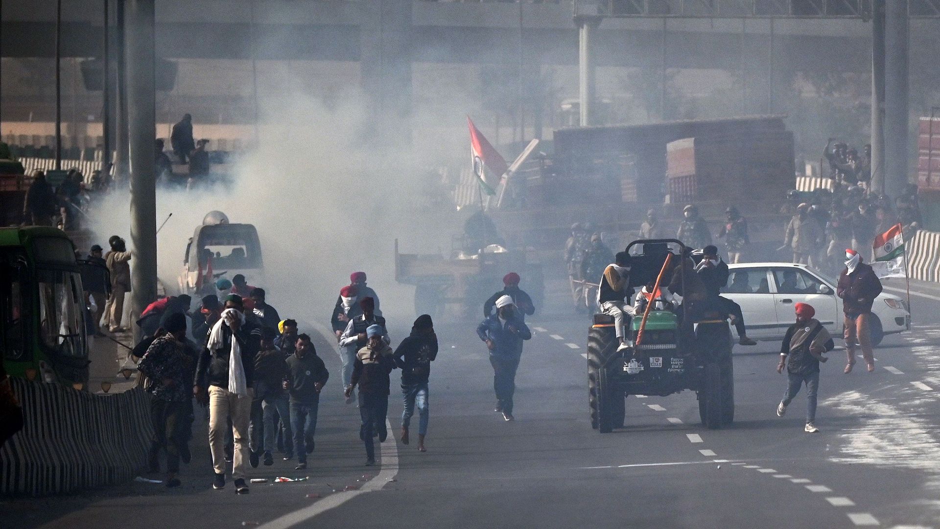 Farmers ride through the smoke of tear gas fired by the police as farmers continue to protest against the central government's recent agricultural reforms in New Delhi on January 26