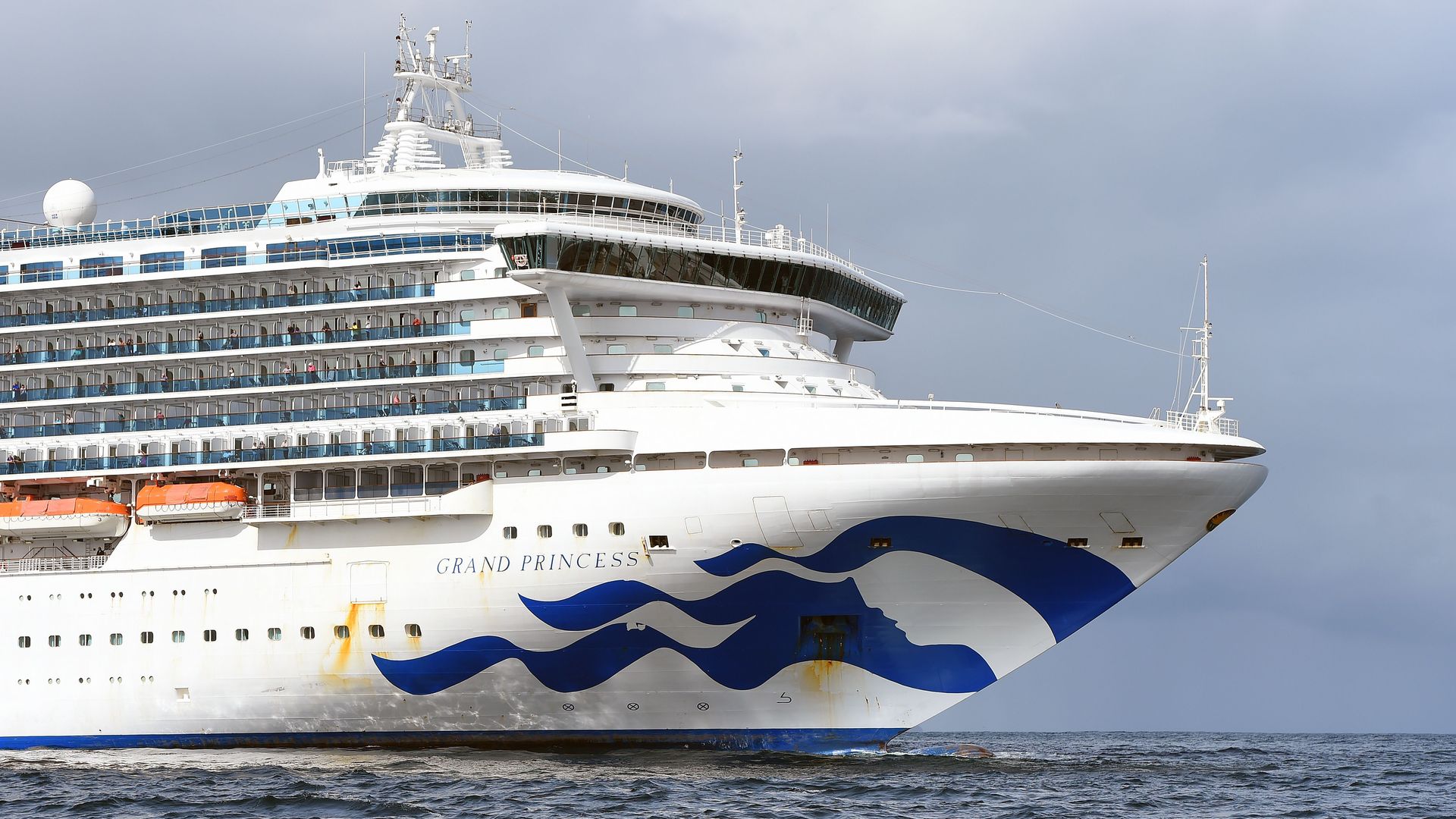 People look out from aboard the Grand Princess cruise ship, operated by Princess Cruises, as it maintains a holding pattern about 25 miles off the coast of San Francisco
