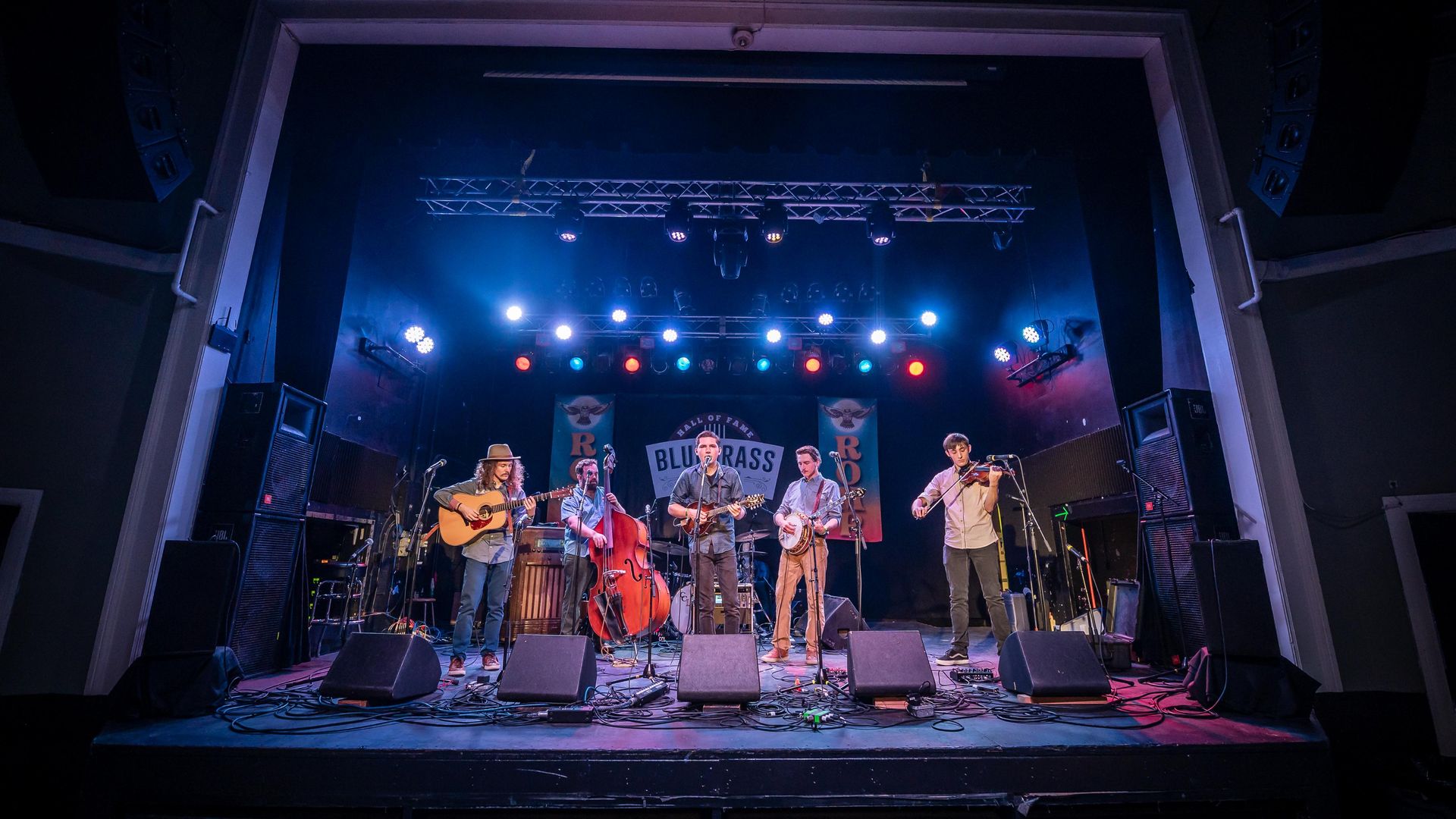 A bluegrass band plays under blue stage lights. 