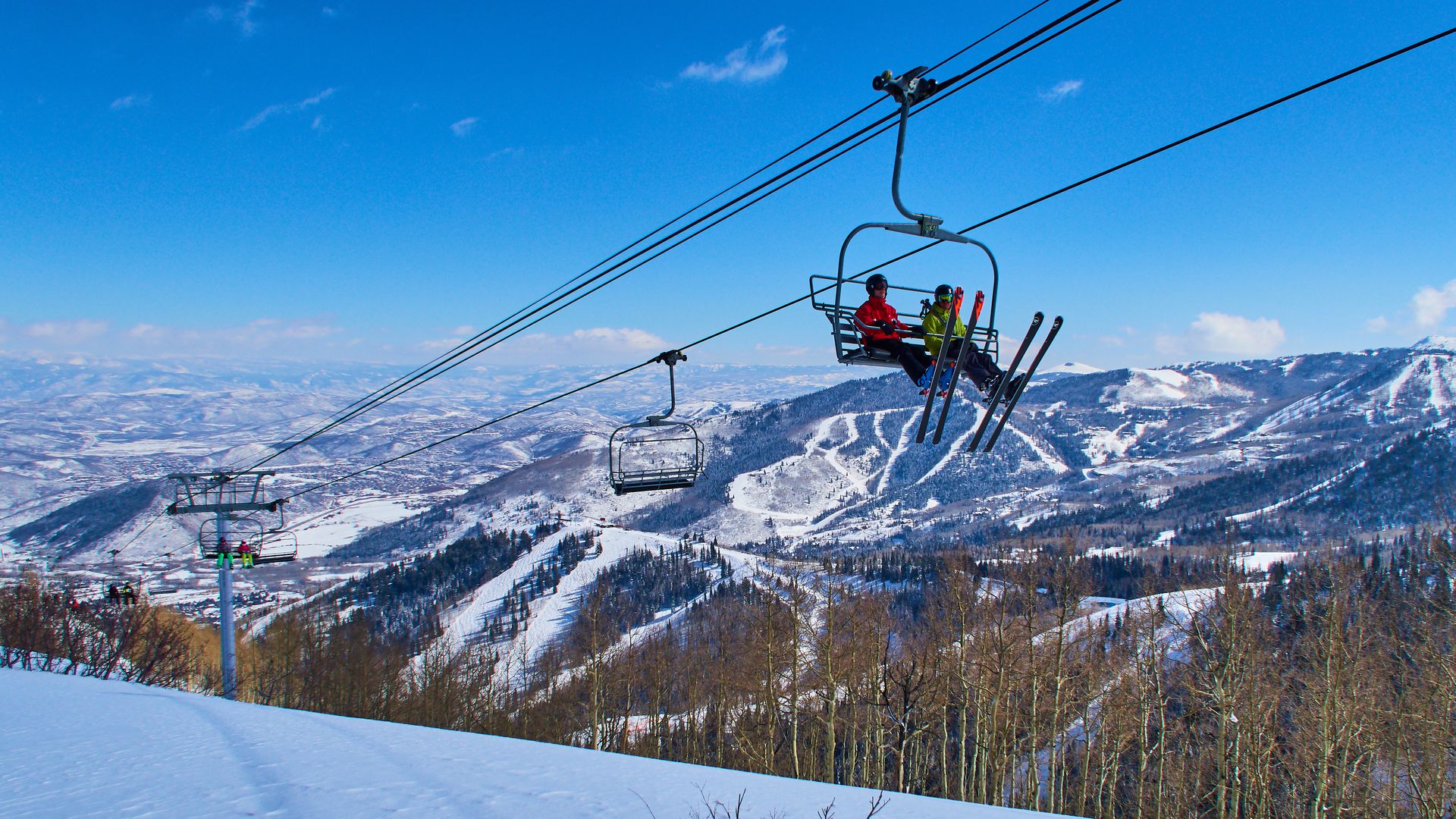 Two skiers are sitting in a chair lift with panoramic view of the Wasatch Range in the Rocky Mountains  in Park City, Utah. Photo: EyesWideOpen/Getty Images