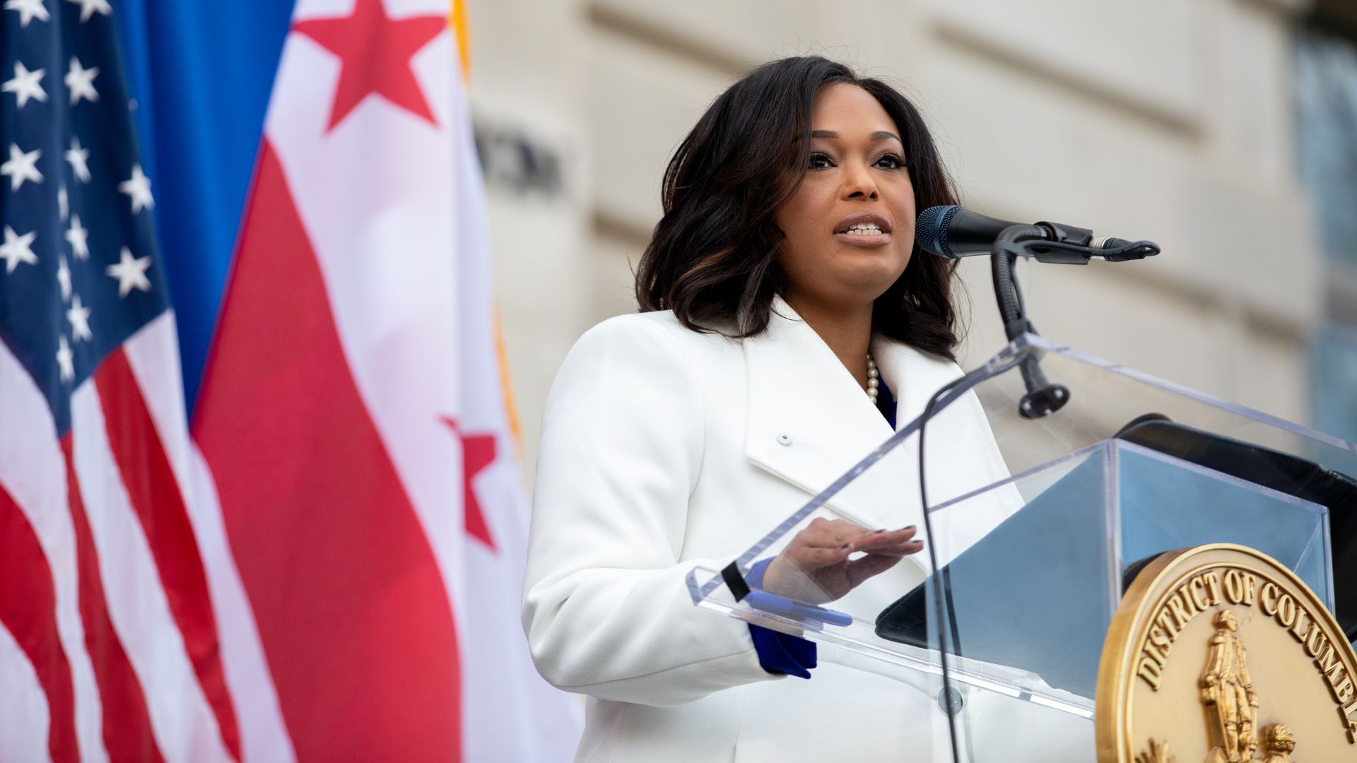 Janeese Lewis George stands outside D.C.'s Wilson Building, speaking at a podium during a ceremony