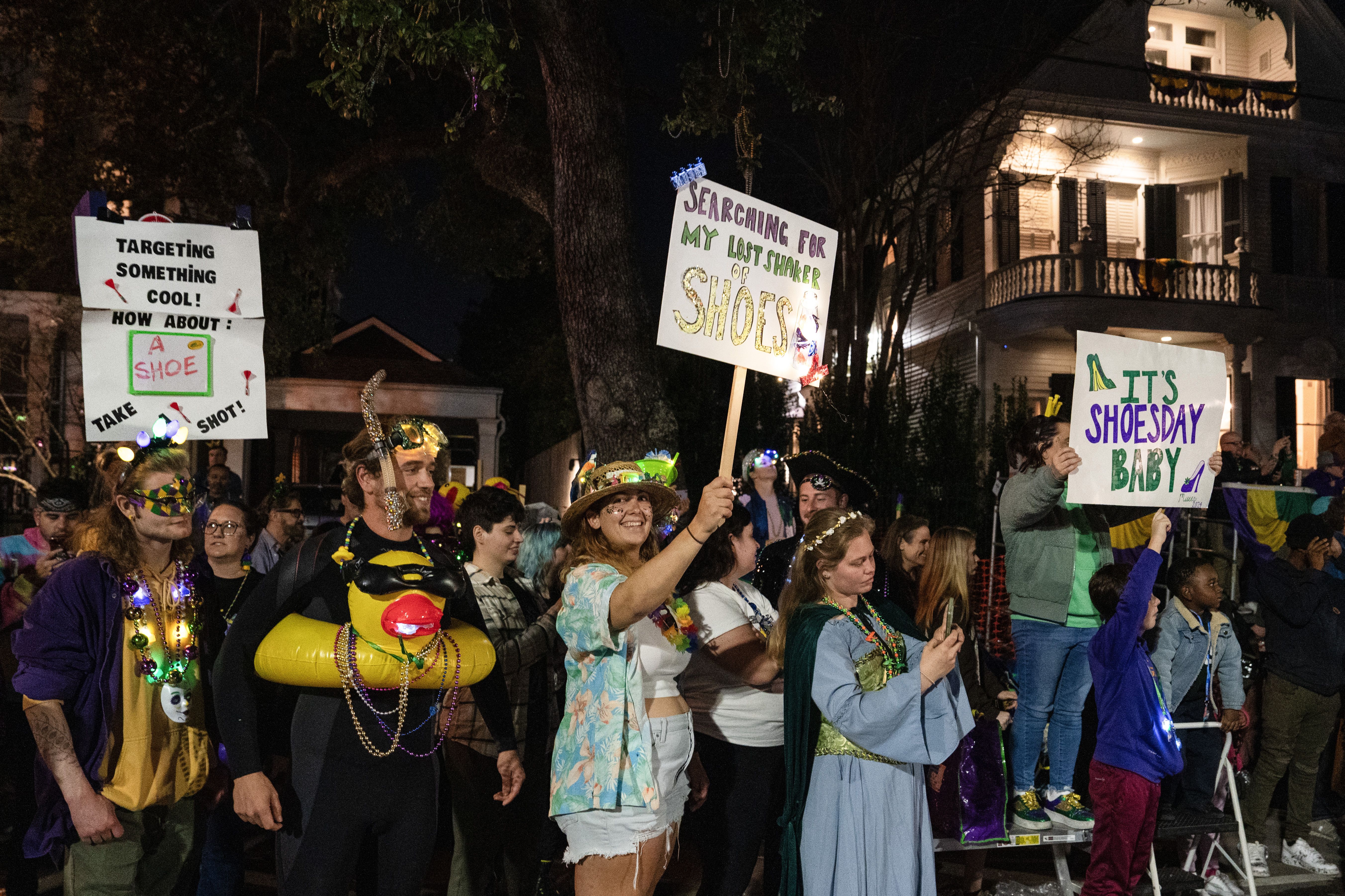 Photo shows paradegoers with signs at the Krewe of Muses parade