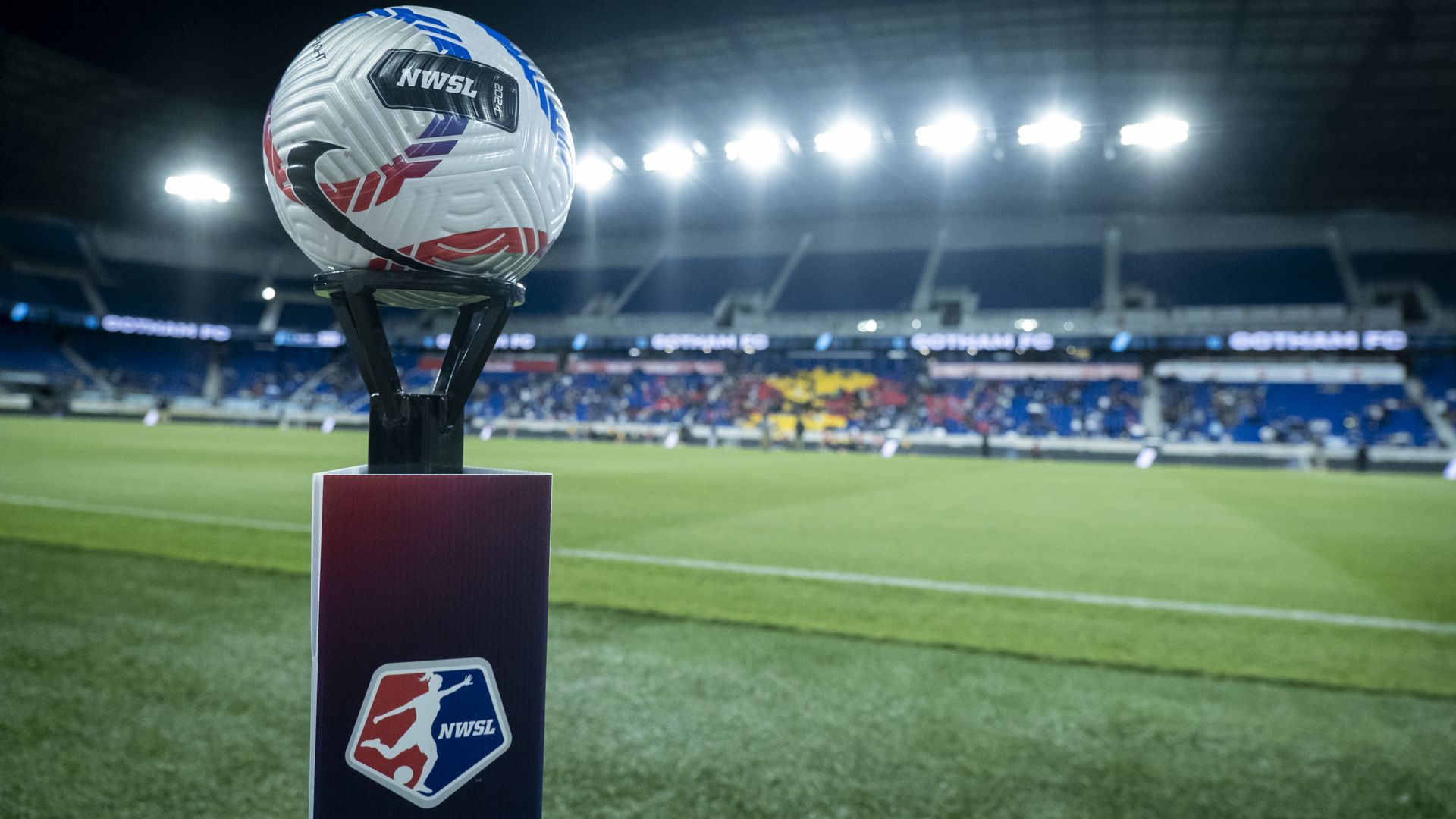 The official NWSL game ball sits on top of a pedestal with the NWSL Logo on it with the stadium behind the ball