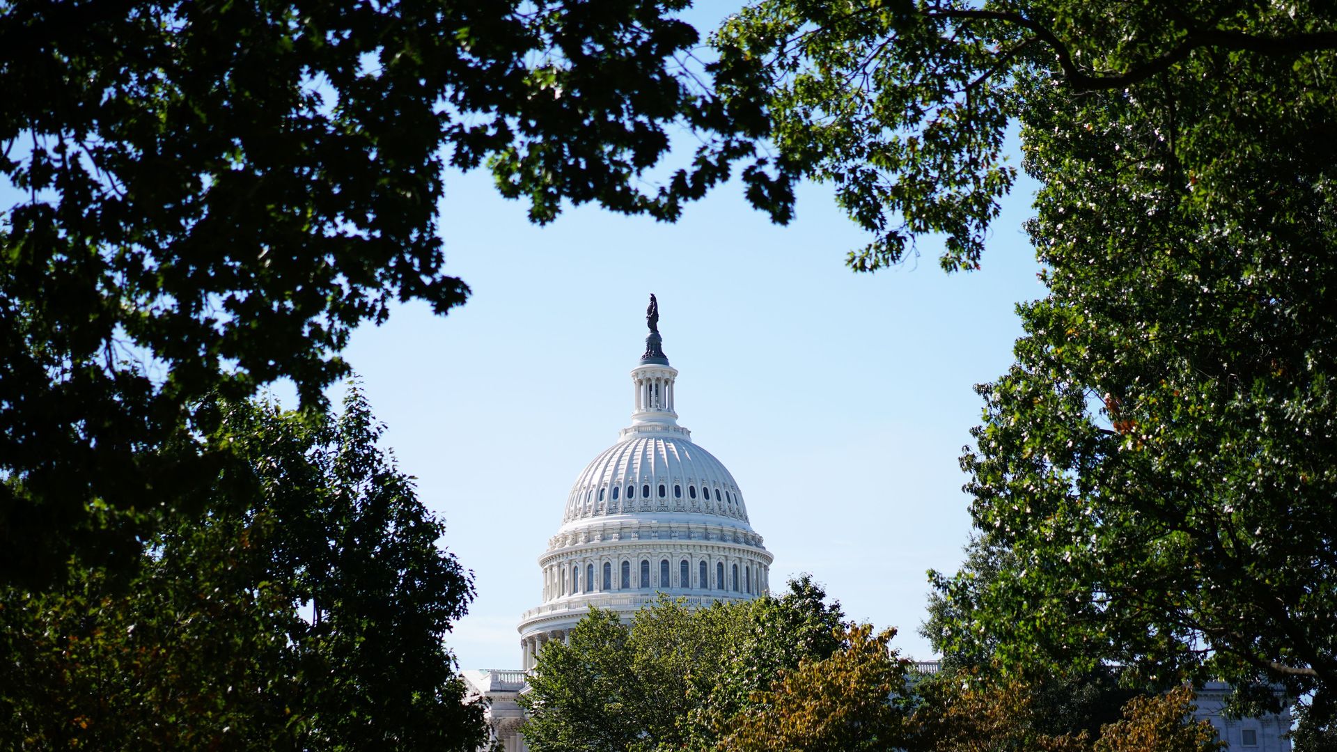 A long view of the U.S. Capitol Building surrounded by trees.