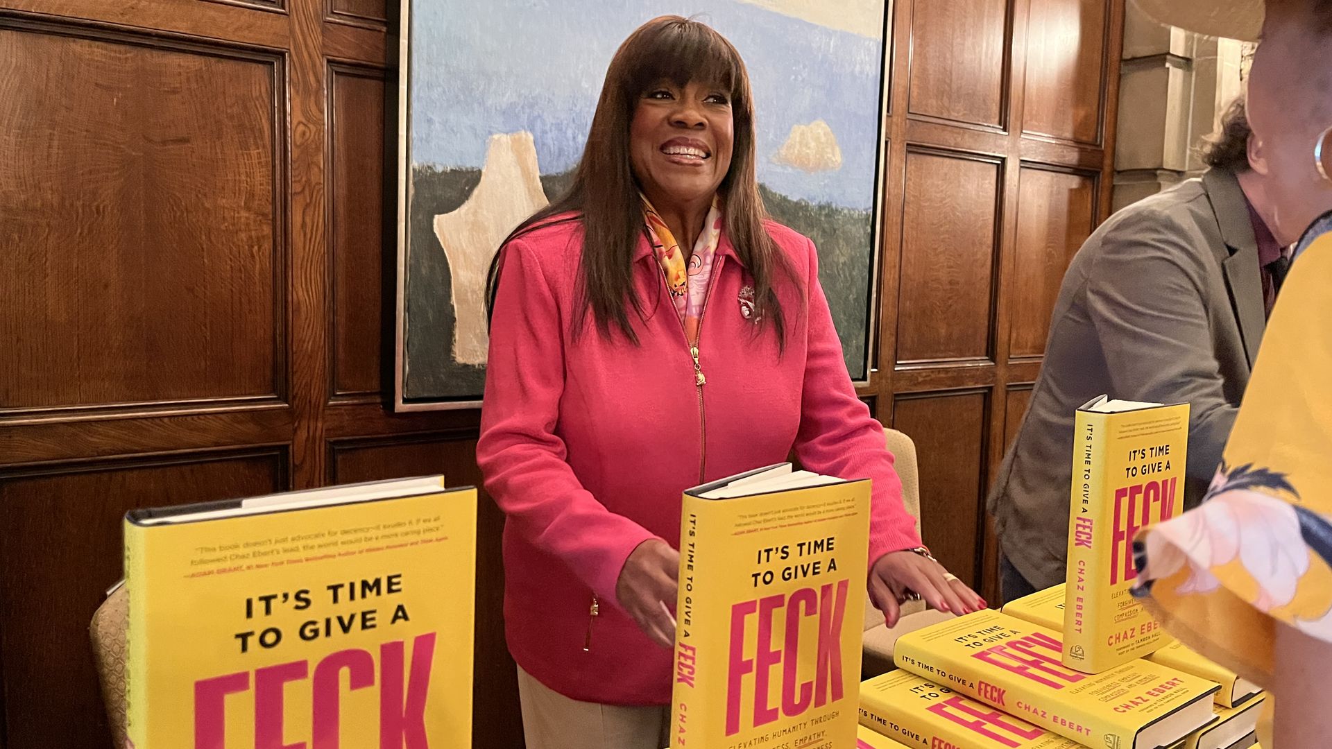 Woman in pink jacket in front of yellow books 
