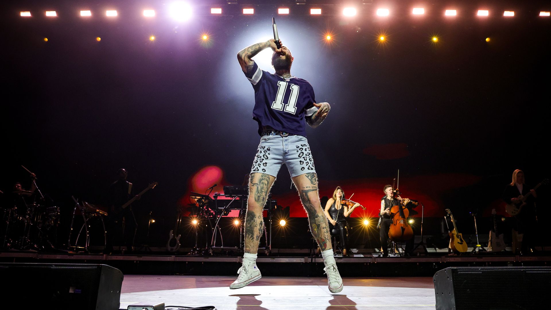  A photo of Post Malone wearing a Cowboys jersey and shorts singing 