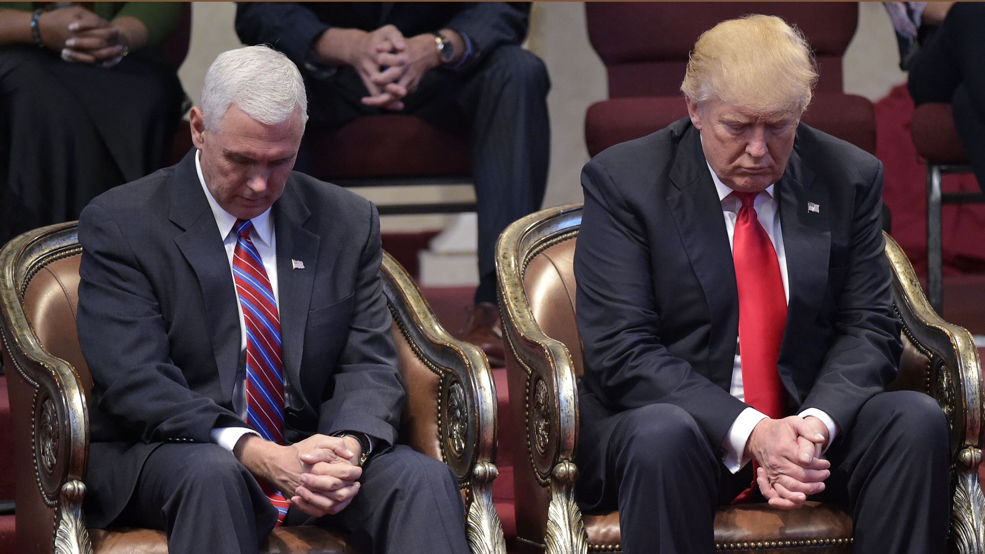 Pence and Trump sit with clasped hands and bowed heads