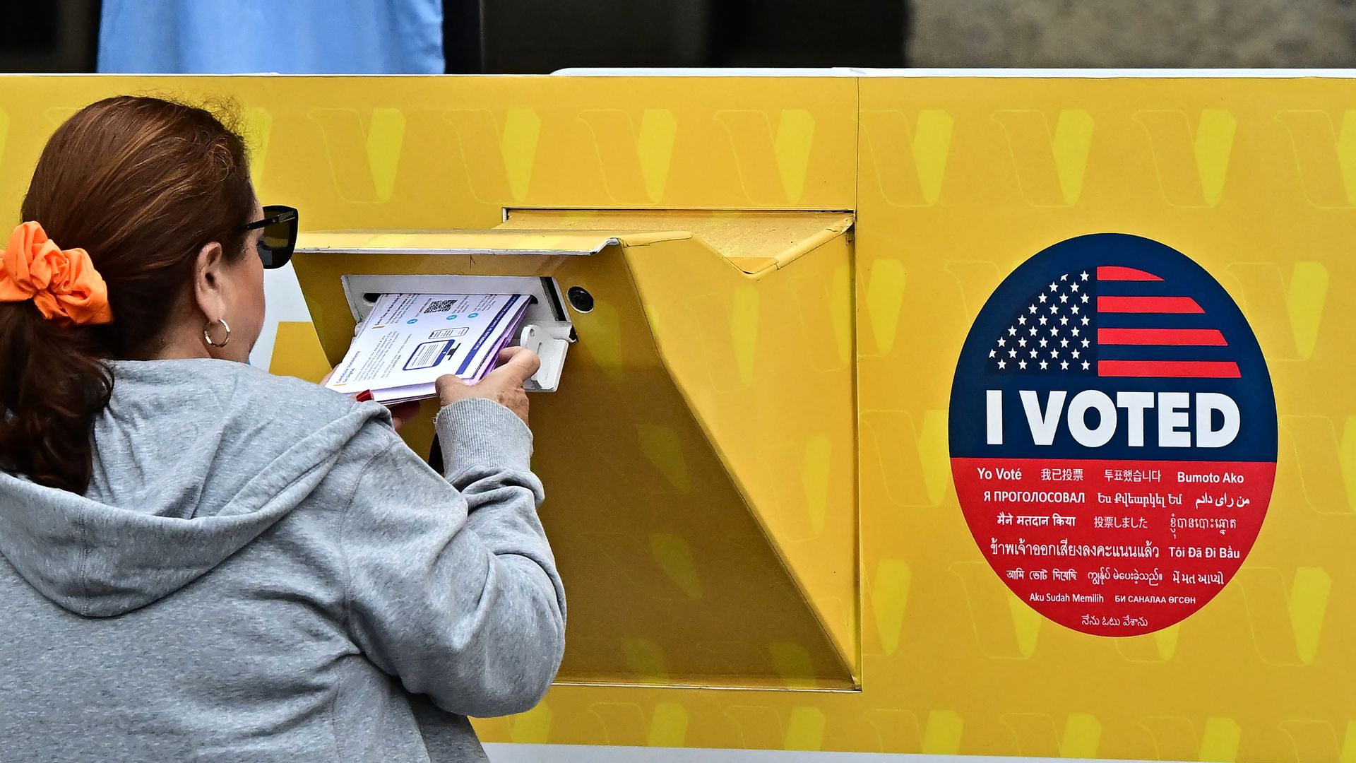 A woman drops off her ballot in a yellow dropbox that says "I voted" at the Los Angeles County Registrar on Oct. 28.