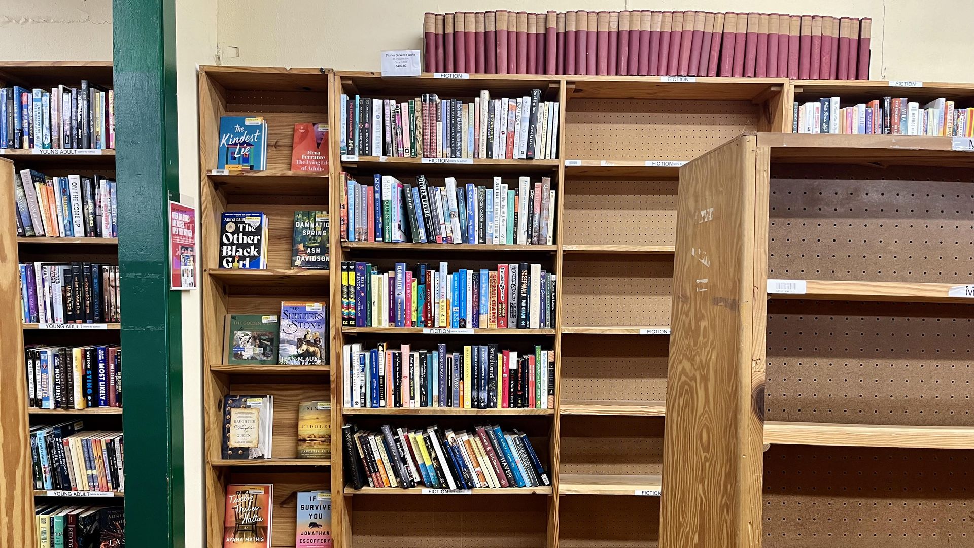 Empty bookshelves next to still-full bookshelves.