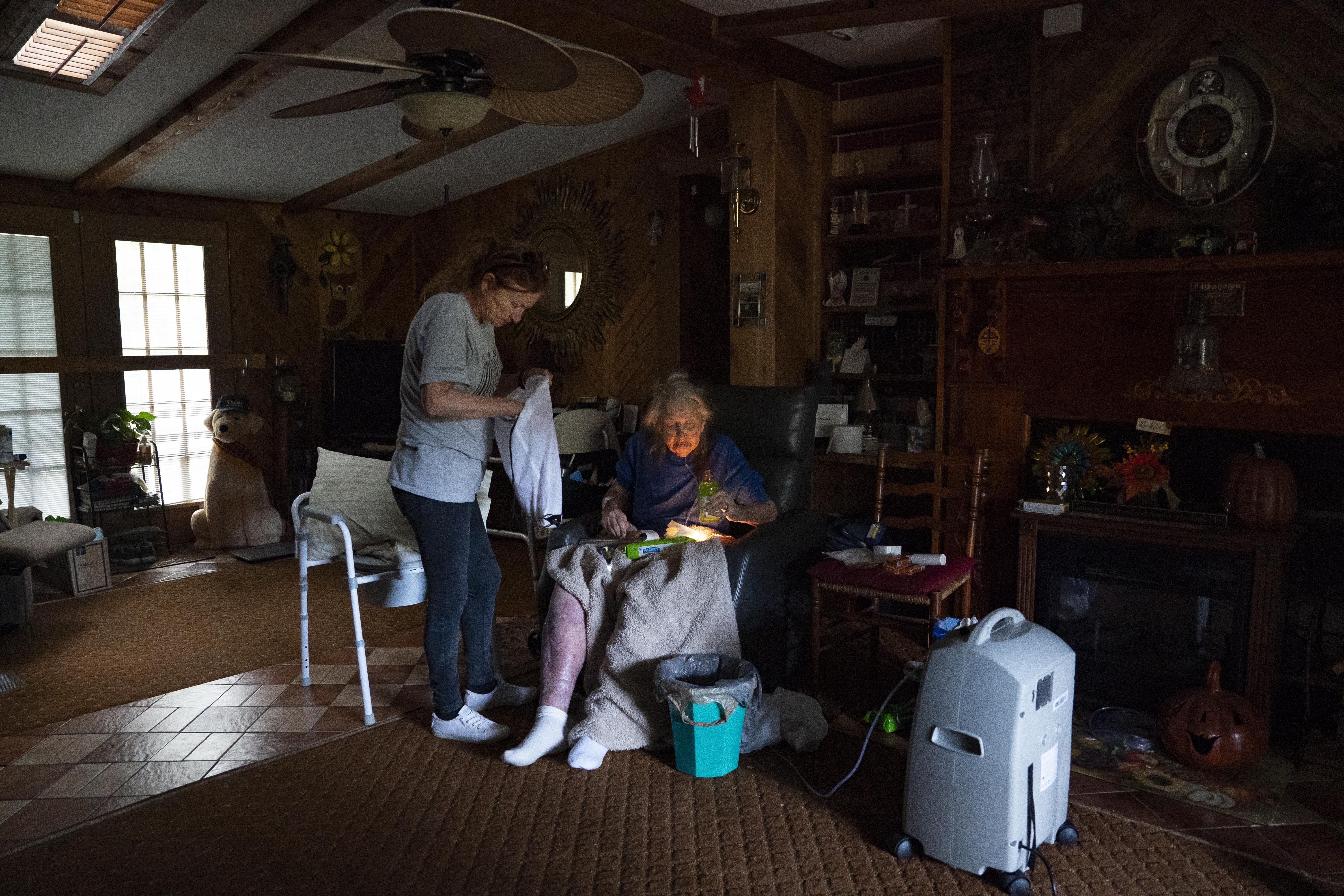 Teresa Rust (L) brings supplies to her neighbor, 94-year-old Barbara Sams, who is powering her oxygen supply with a generator, in Bills Creek, North Carolina, October 2, 2024, after the passage of Hurricane Helene.