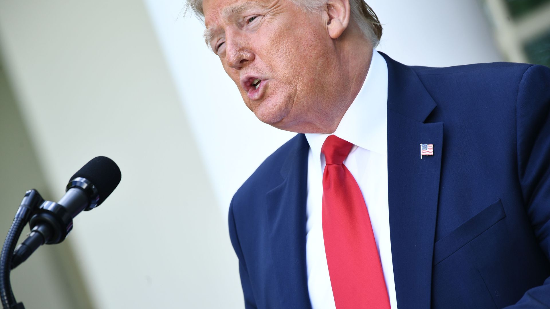 In this image, Trump wears a tie and speaks to reporters