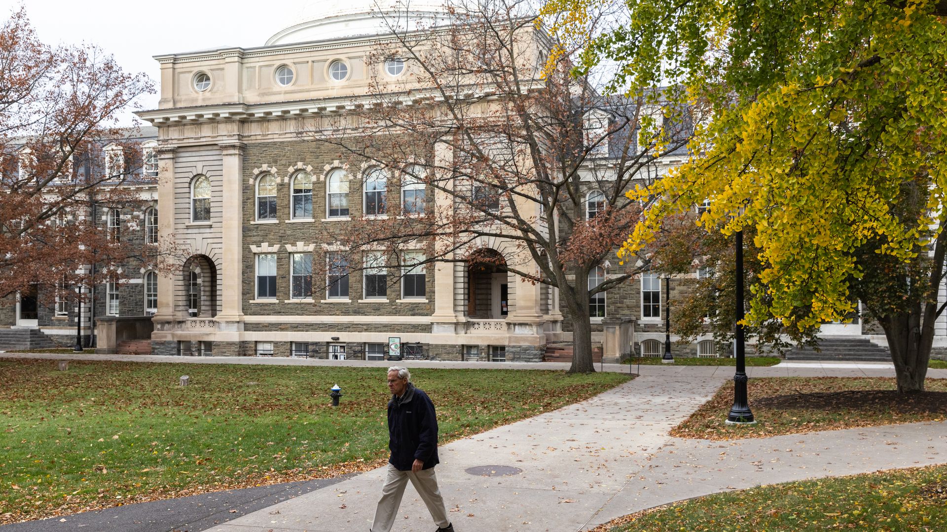 A man walks in front of a building on Cornell University's campus.