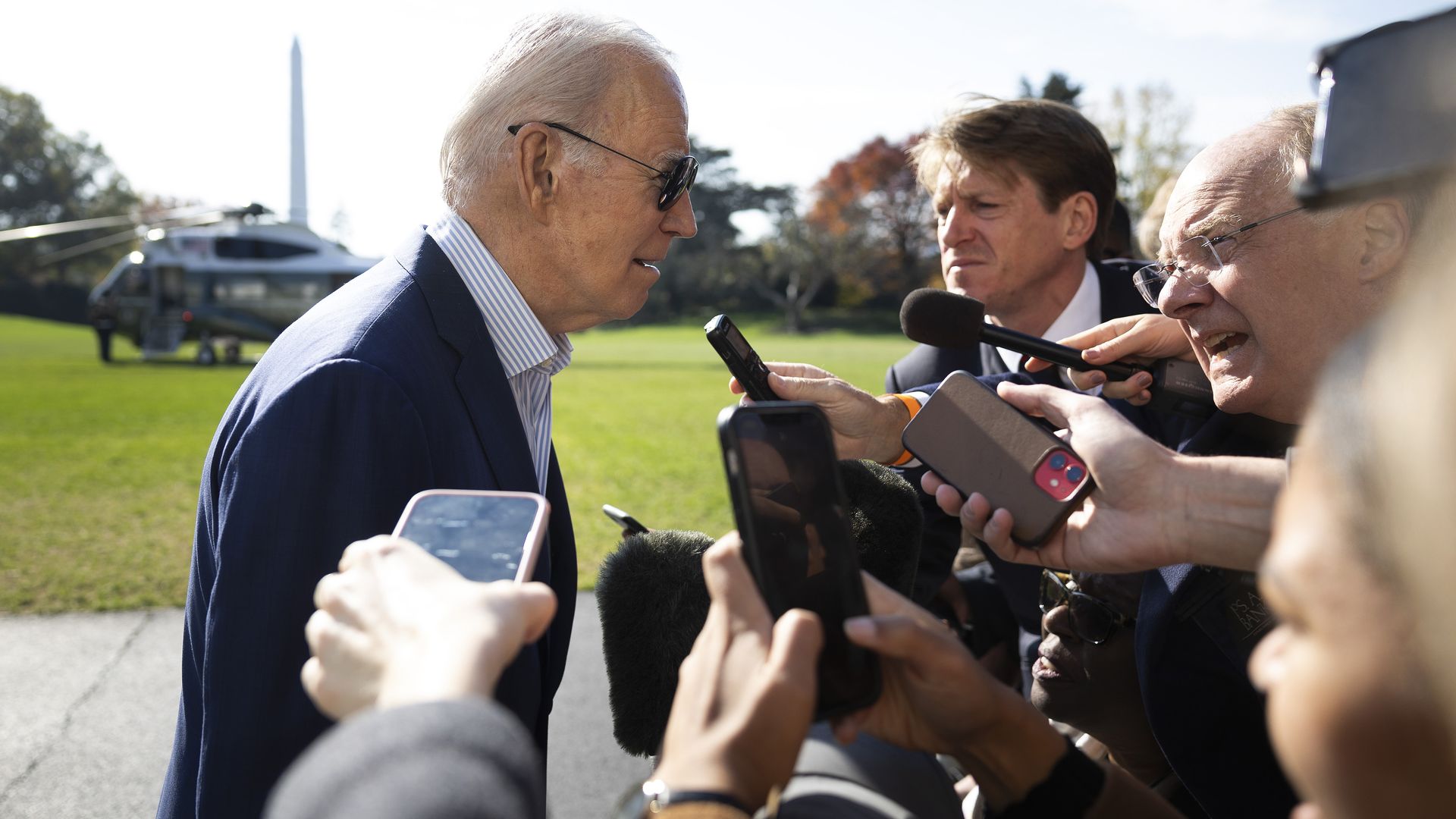 President Biden is shown talking with reporters on the South Lawn of the White House