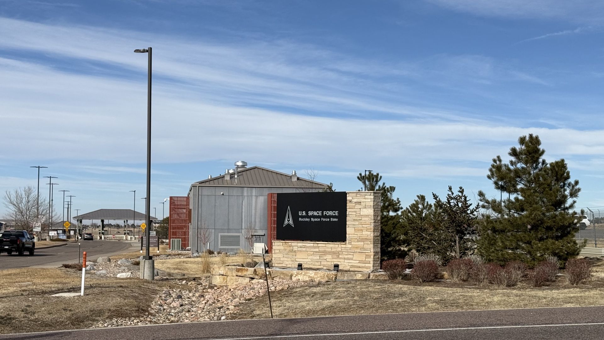 A sign that reads US SPACE FORCE outside an area with trees, grass and some rocks. 