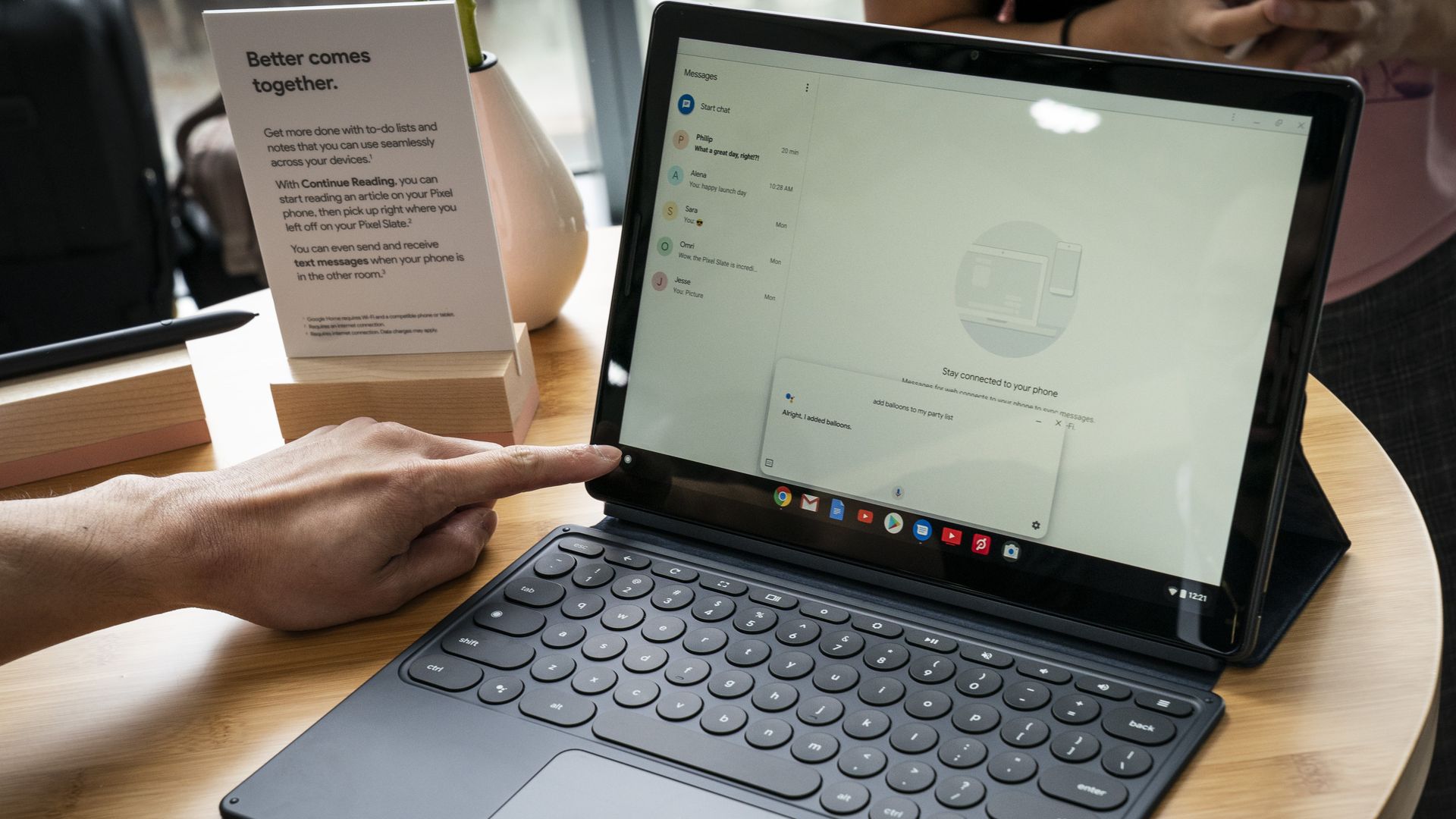 This image shows someone reaching for the keyboard of a Pixel Slate that's sitting on a table.