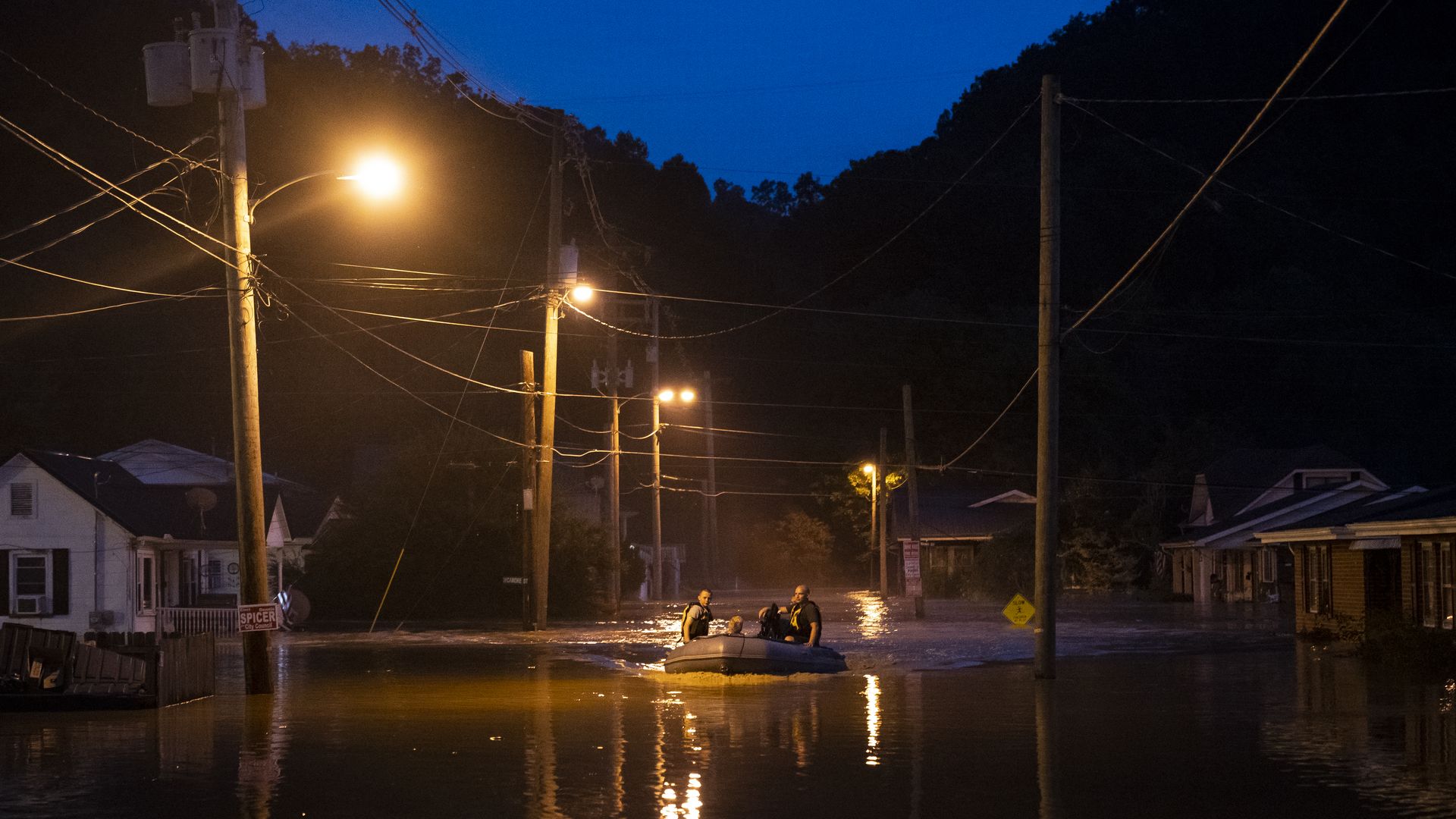 A search and rescue team navigates a flood by boat. 