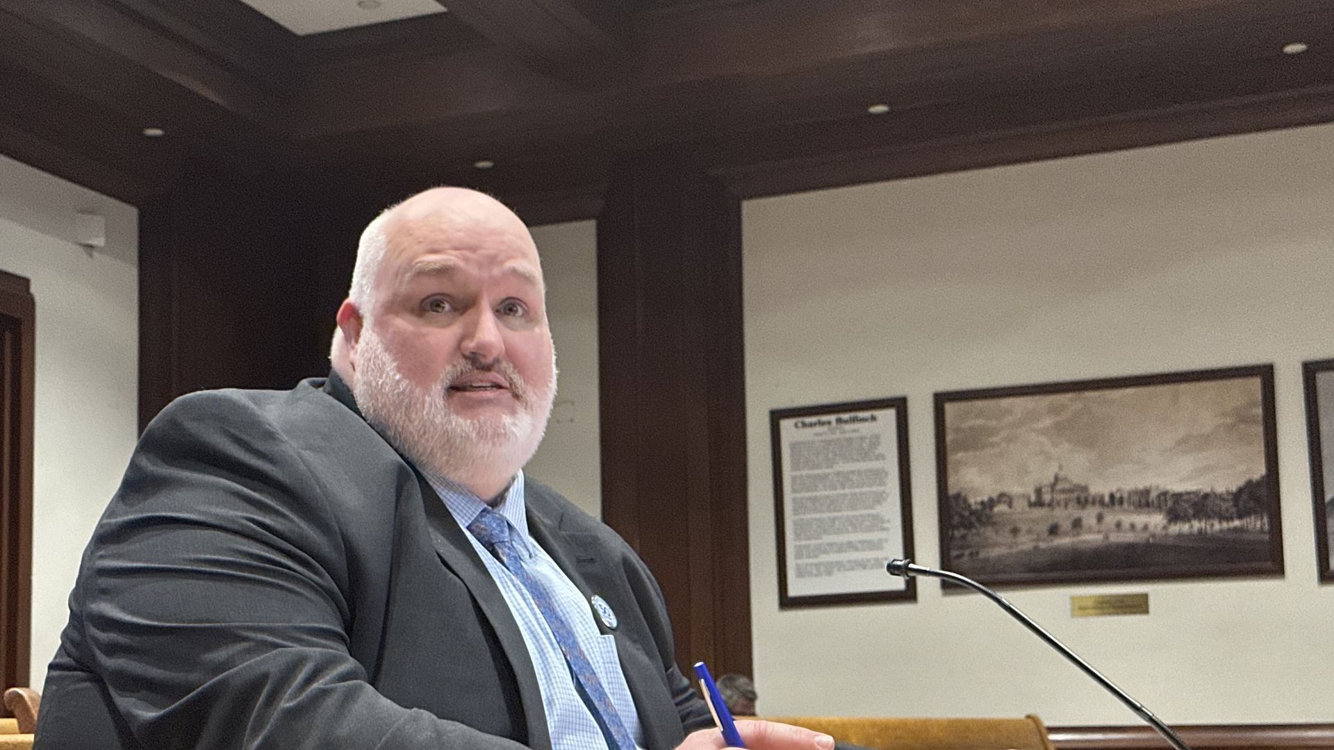 Mark Bracken, interim executive director of the lottery, sits at a table in a Massachusetts State House room while testifying during a legislative hearing.