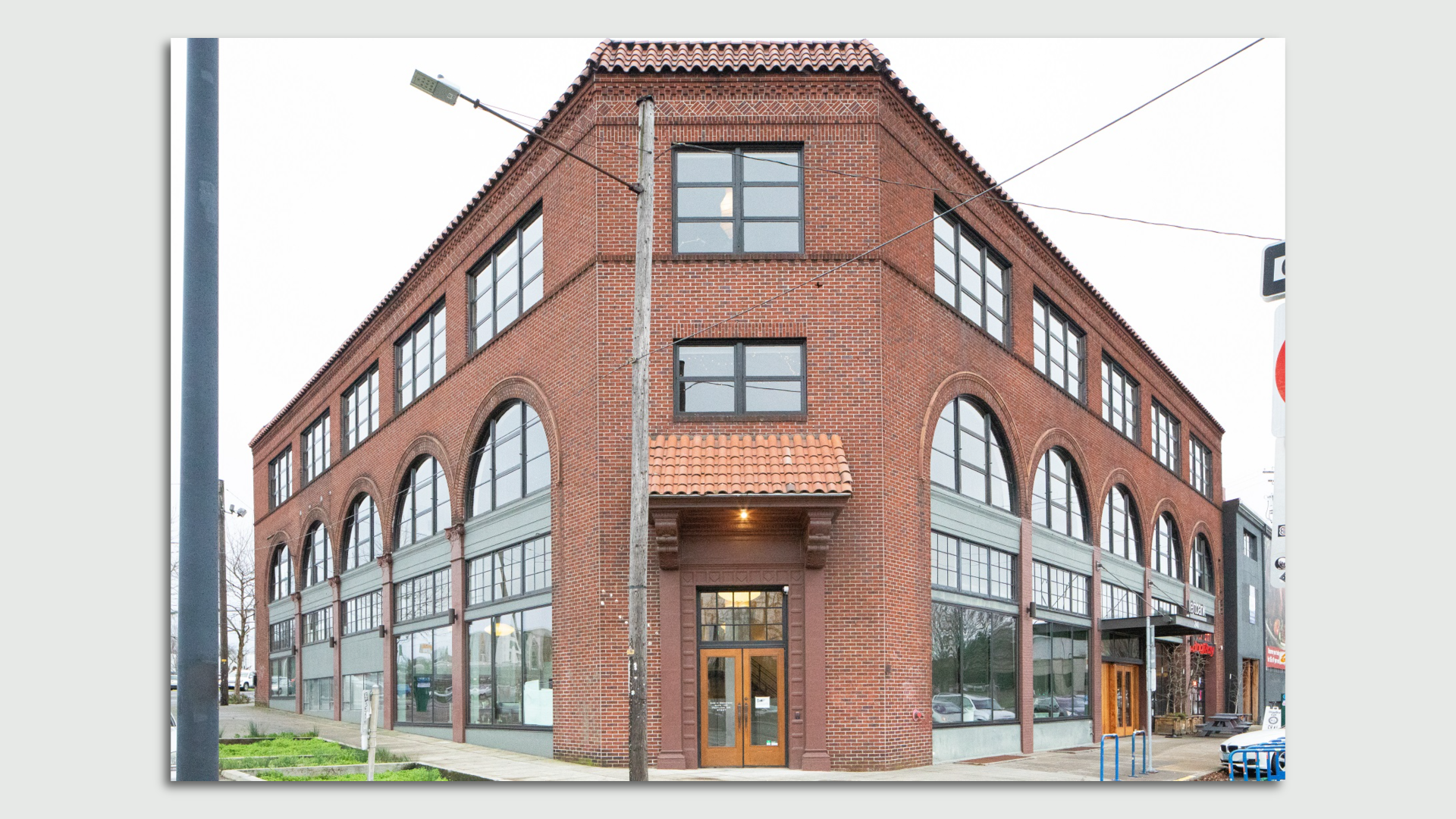 A photo of the exterior of a three-story brick building with large glass windows.