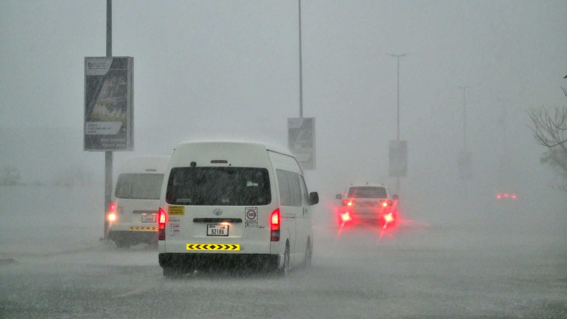 A photo of heavy rain falling as trucks drive into flooded waters.