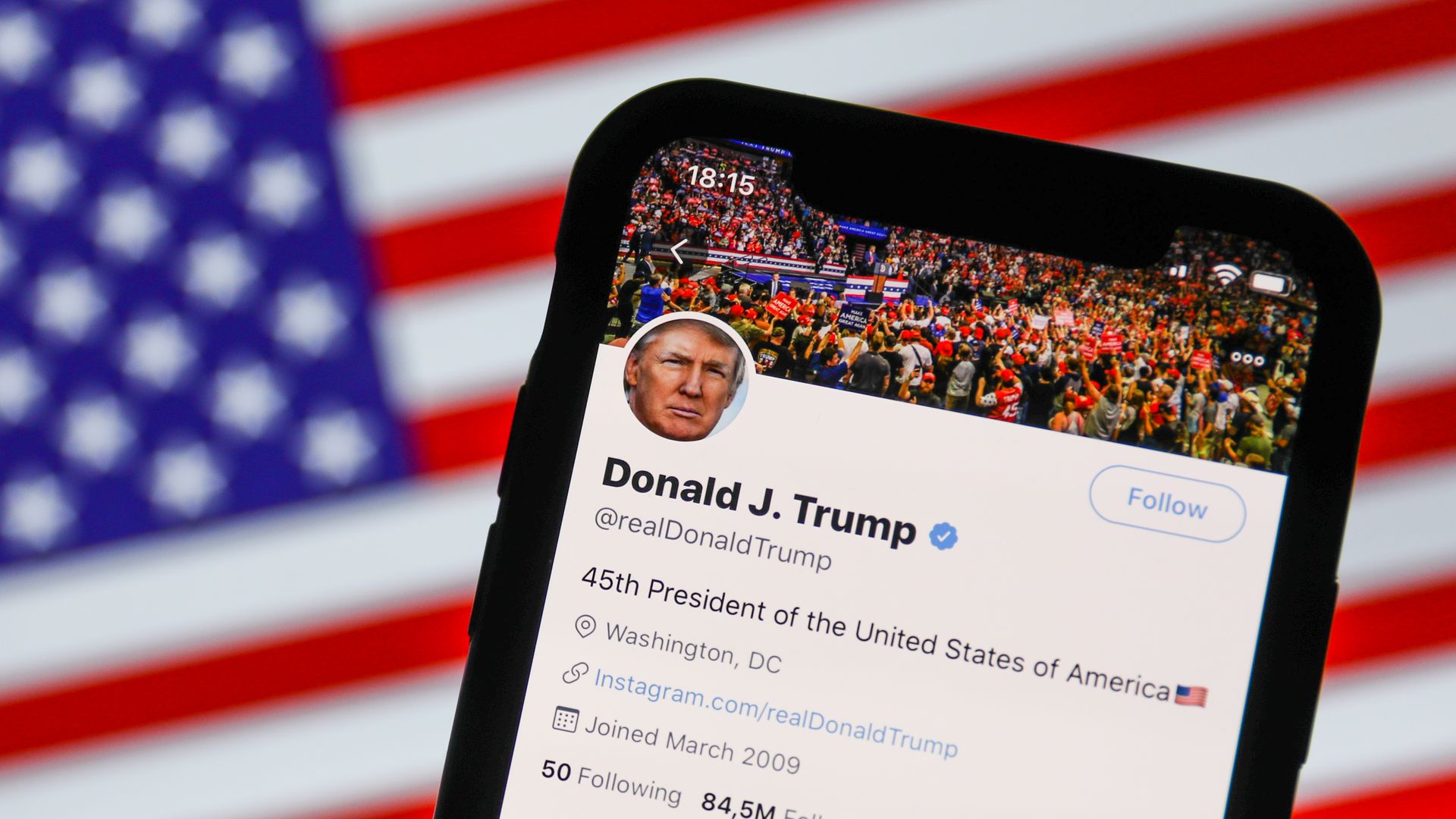 A photo illustration of President Trump's Twitter account on a smartphone screen, with the American flag behind it.
