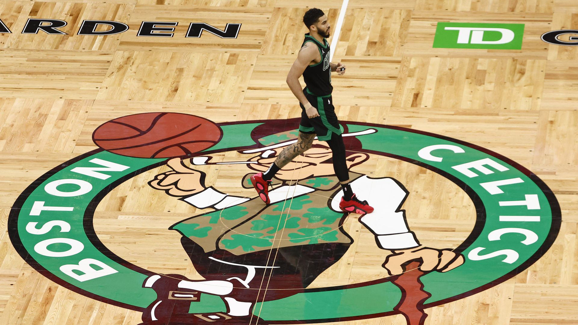 Celtics player Jayson Tatum, No. 0, walks across the Celtics logo on the court in TD Garden during Game 2 against the Indiana Pacers.