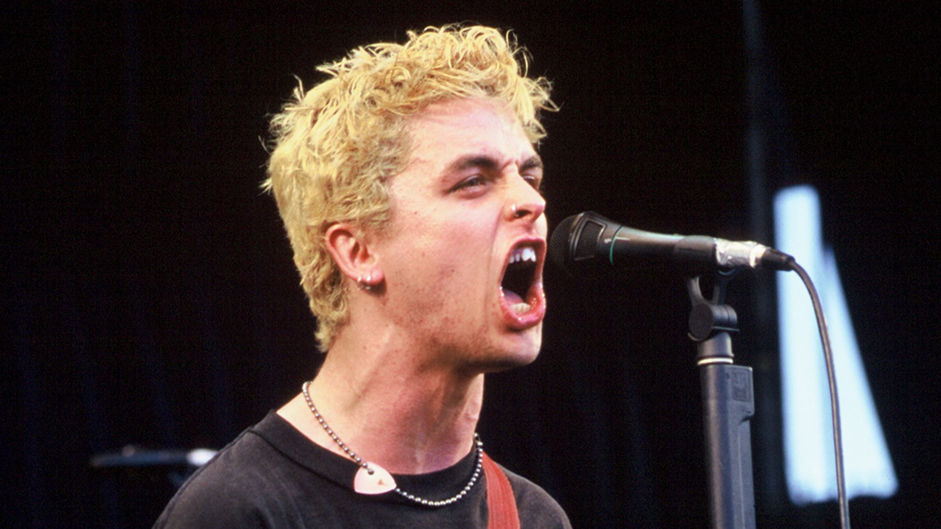 Green Day's lead singer performs on stage in 1994 with blonde hair. 