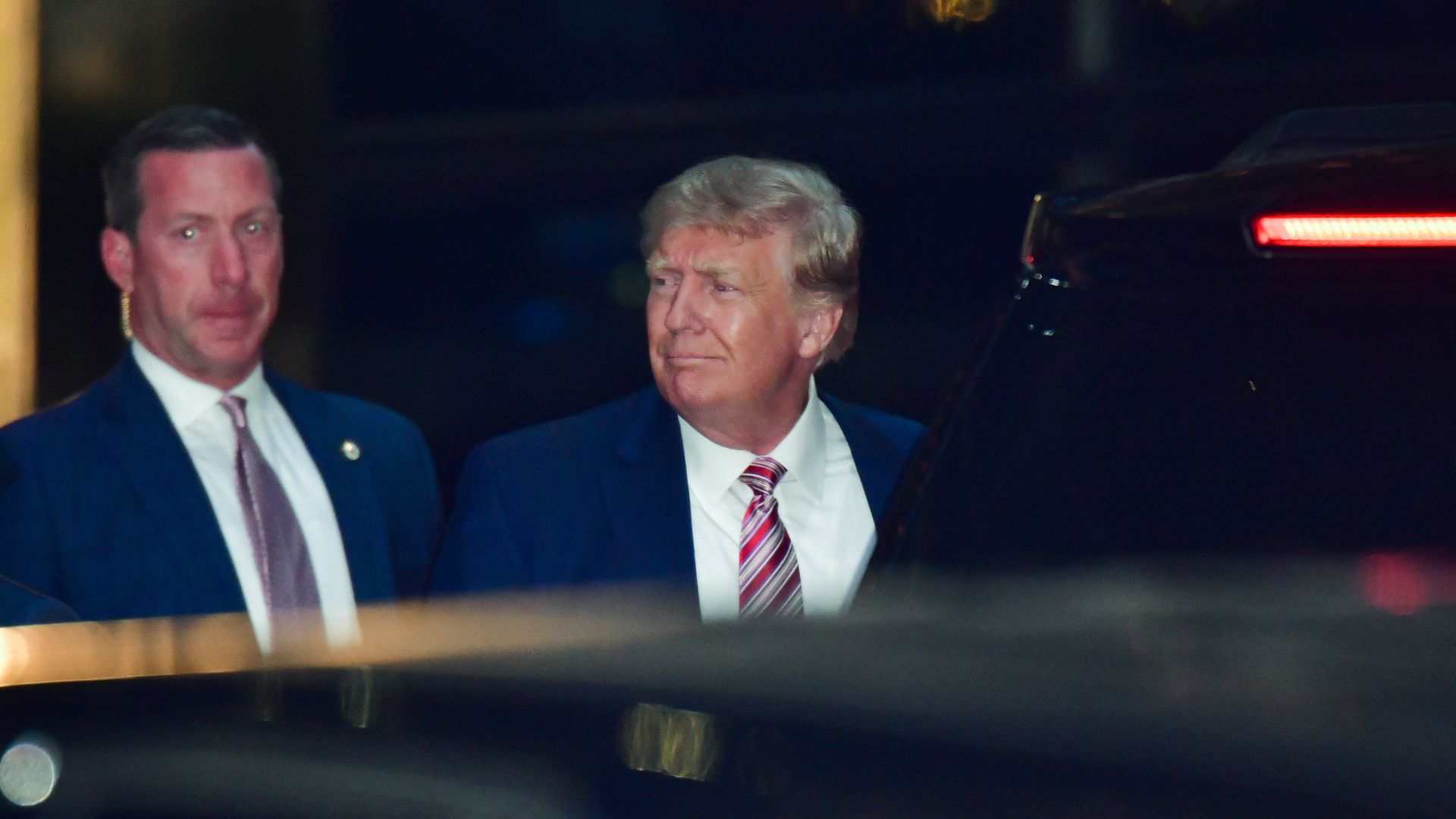 Photo of Donald Trump standing next to a security guard as he looks to his right